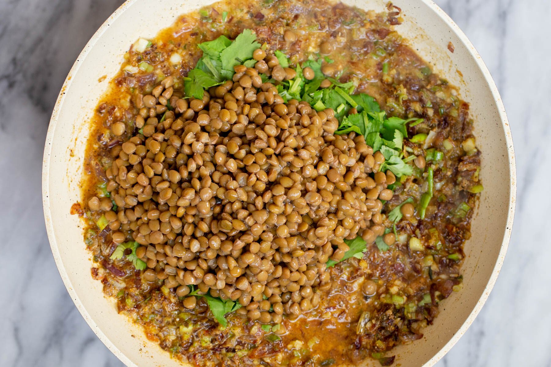 lentils being added to sauteed garlic, ginger and onions to make pie filling