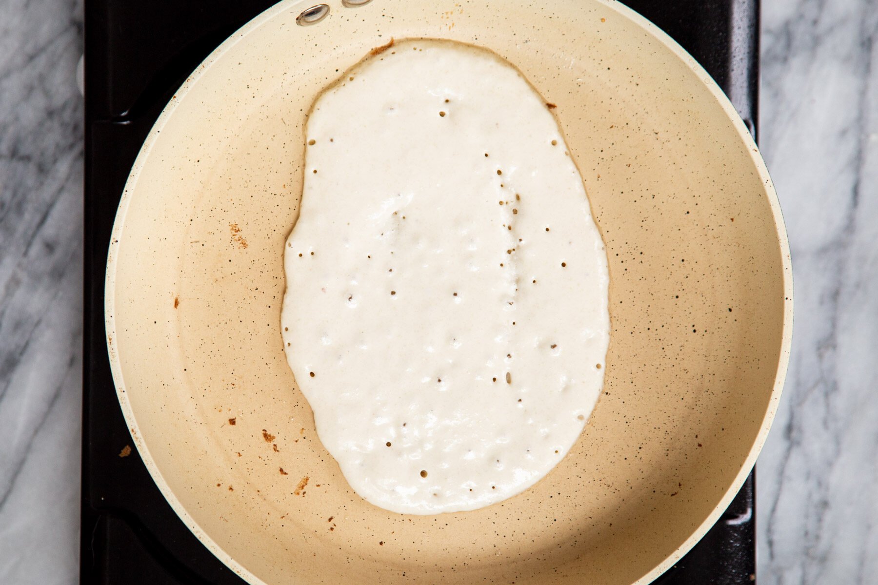 vegan naan batter being added to a pan
