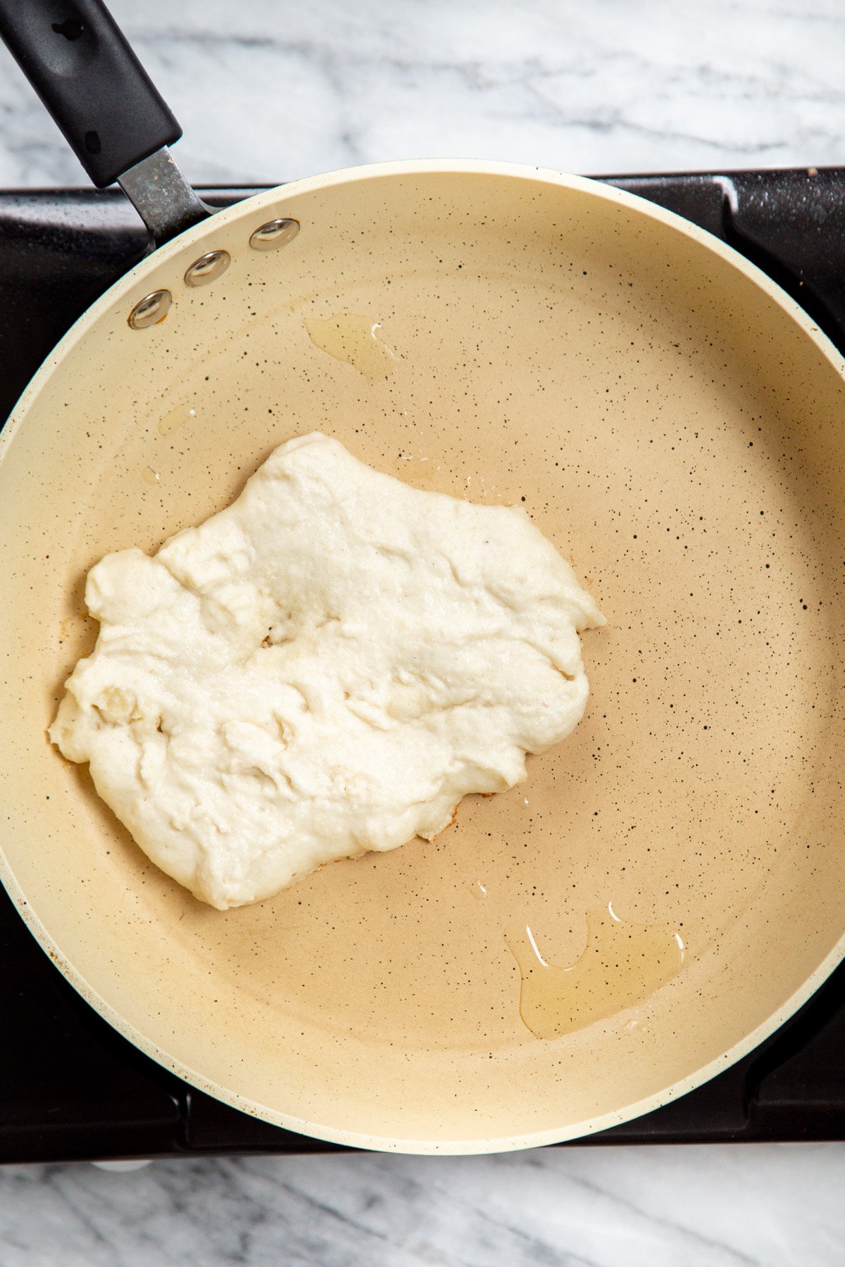 Almond flour Naan batter on white skillet