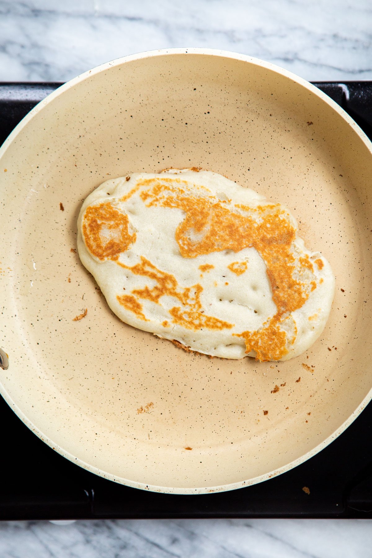 Almond flour Naan batter on white skillet