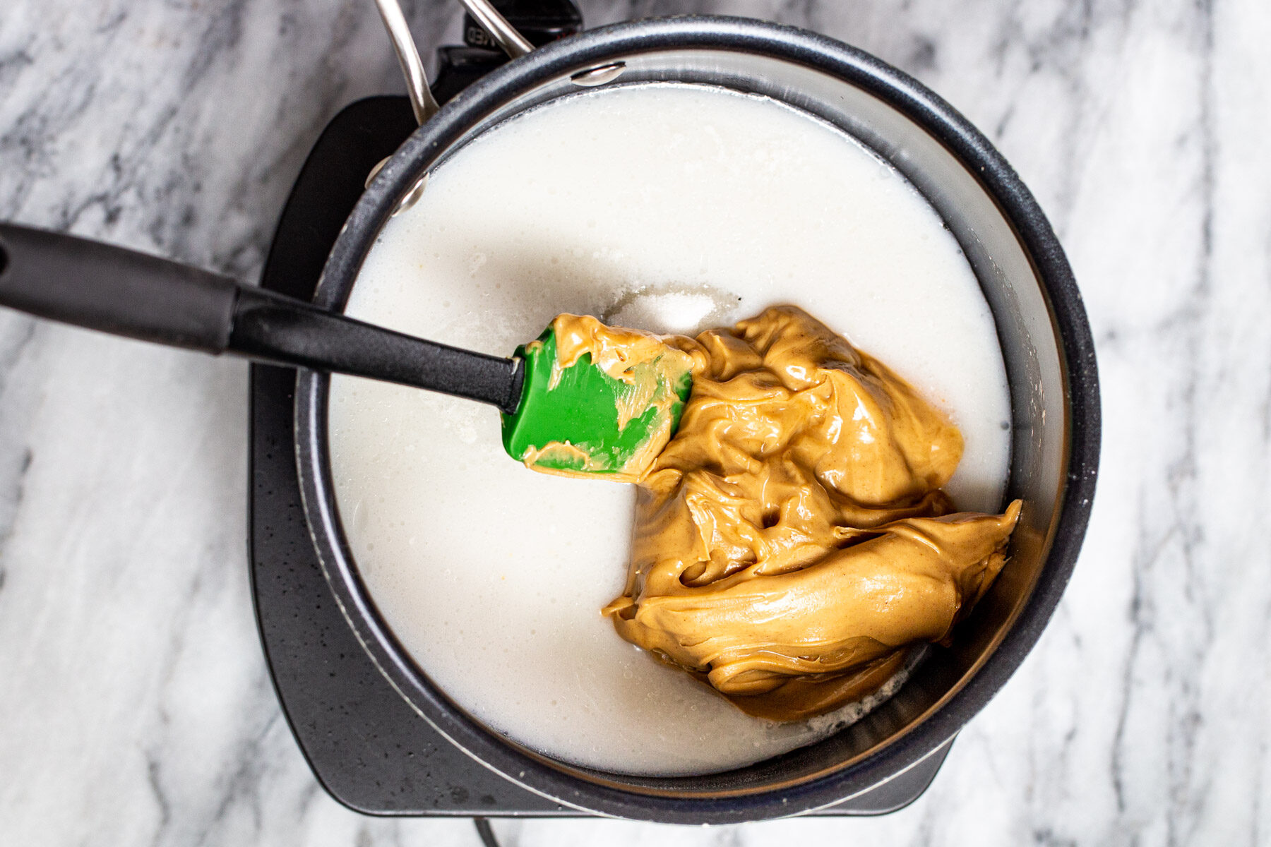 peanut butter being stirred into coconut milk 