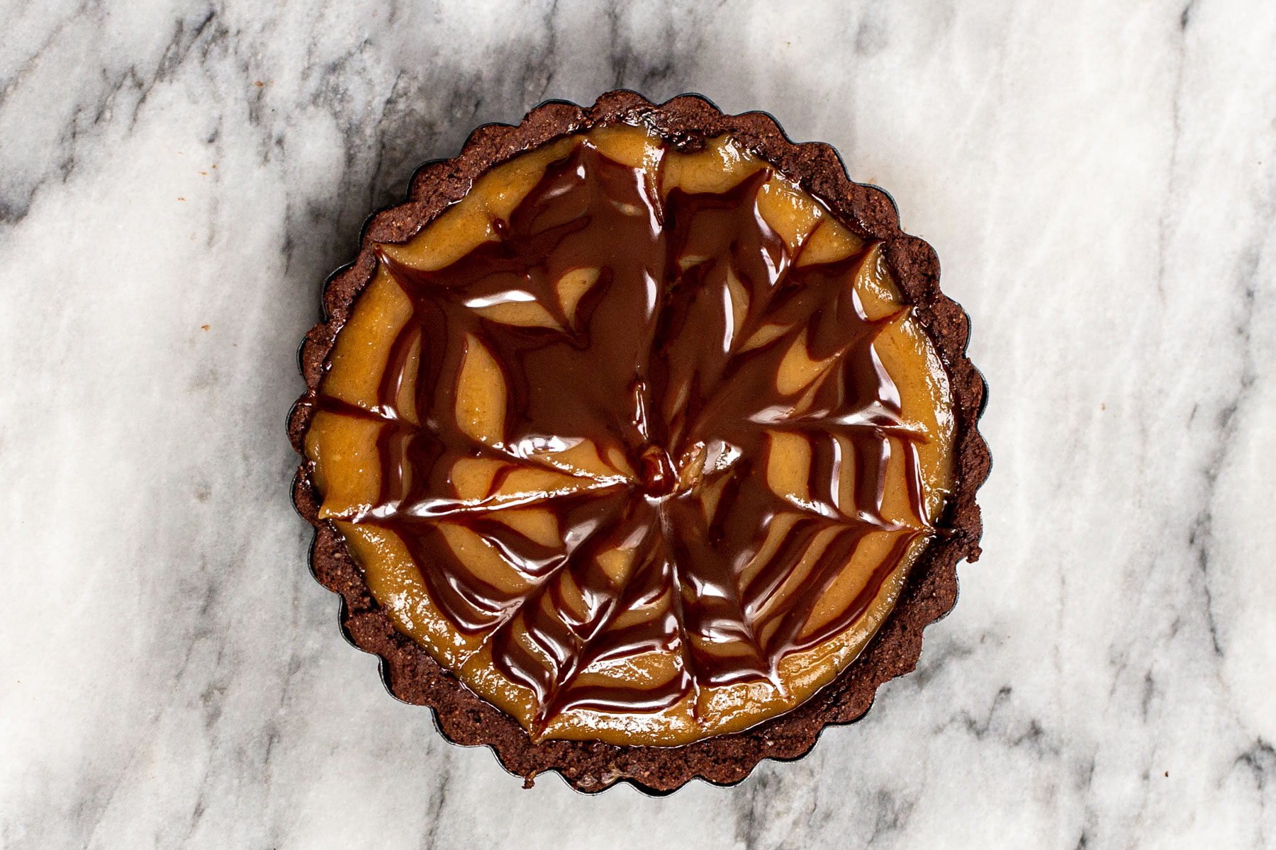 peanut butter chocolate mini tart decorated with a chocolate glaze pattern
