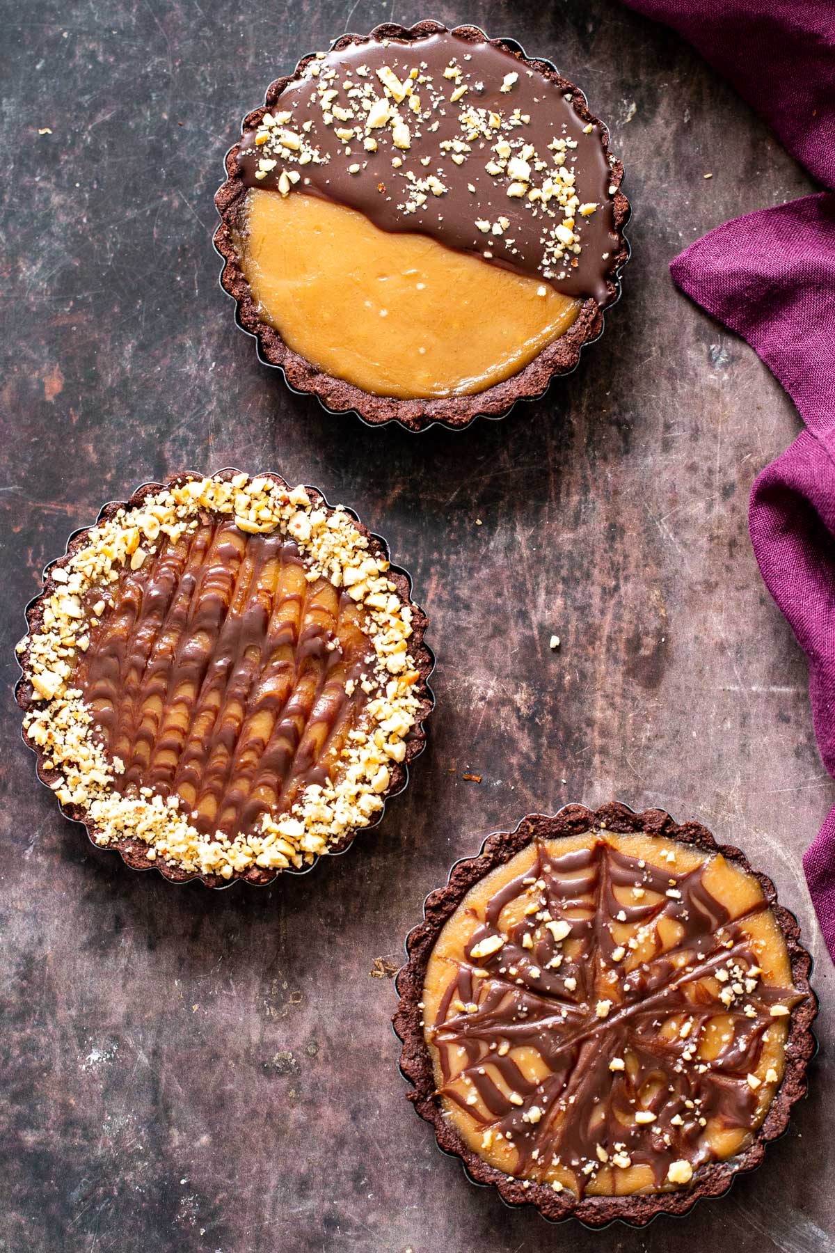 overhead shot of three peanut butter chocolate tarts on a wooden surface 