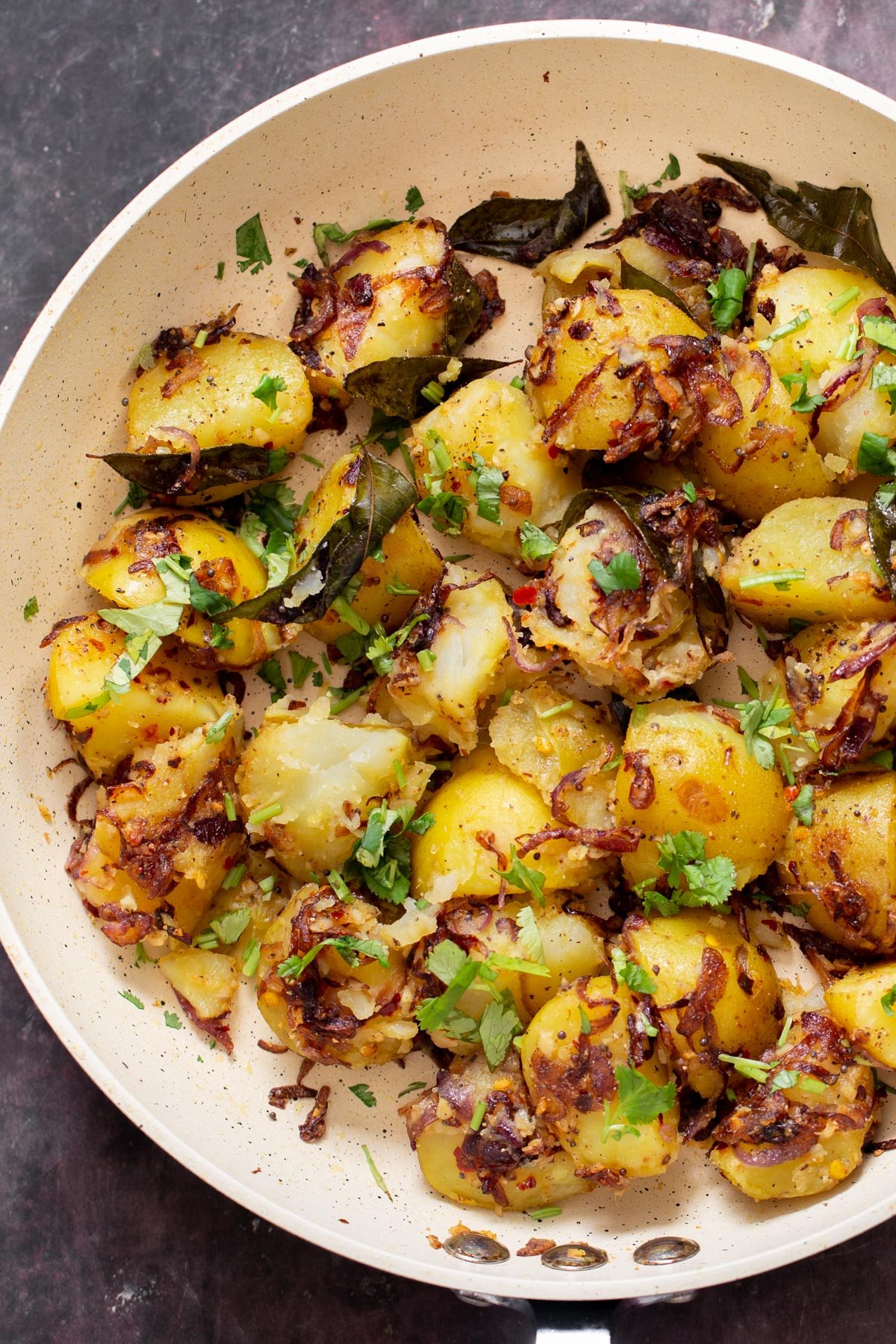 a frying pan with potatoes sprinkled with cilantro