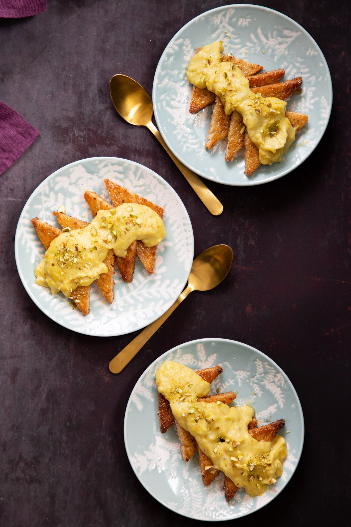 three plates with toast bread soaked in syrup and topped with custard