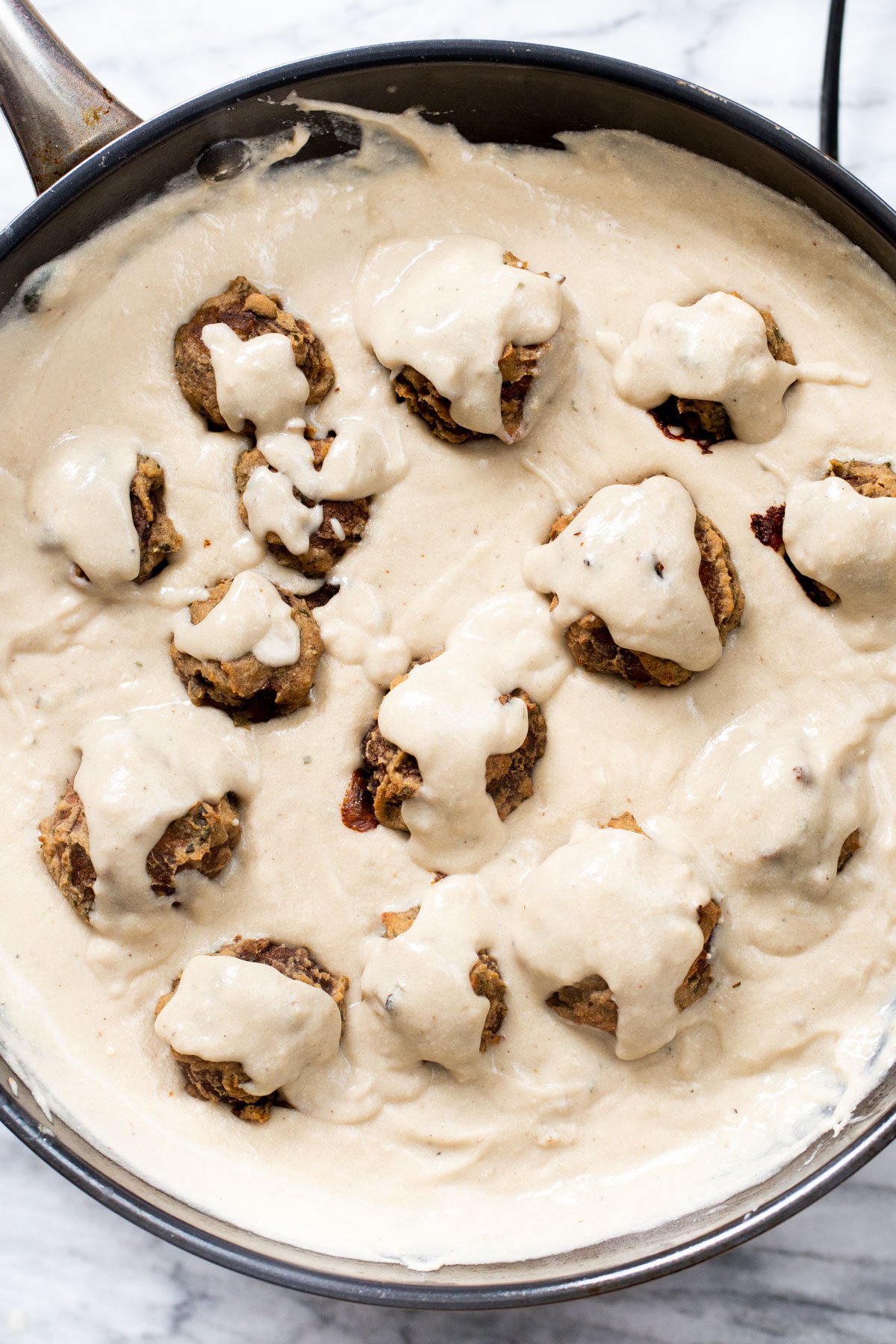 vegan mushroom balls being tossed in vegan mushroom gravy