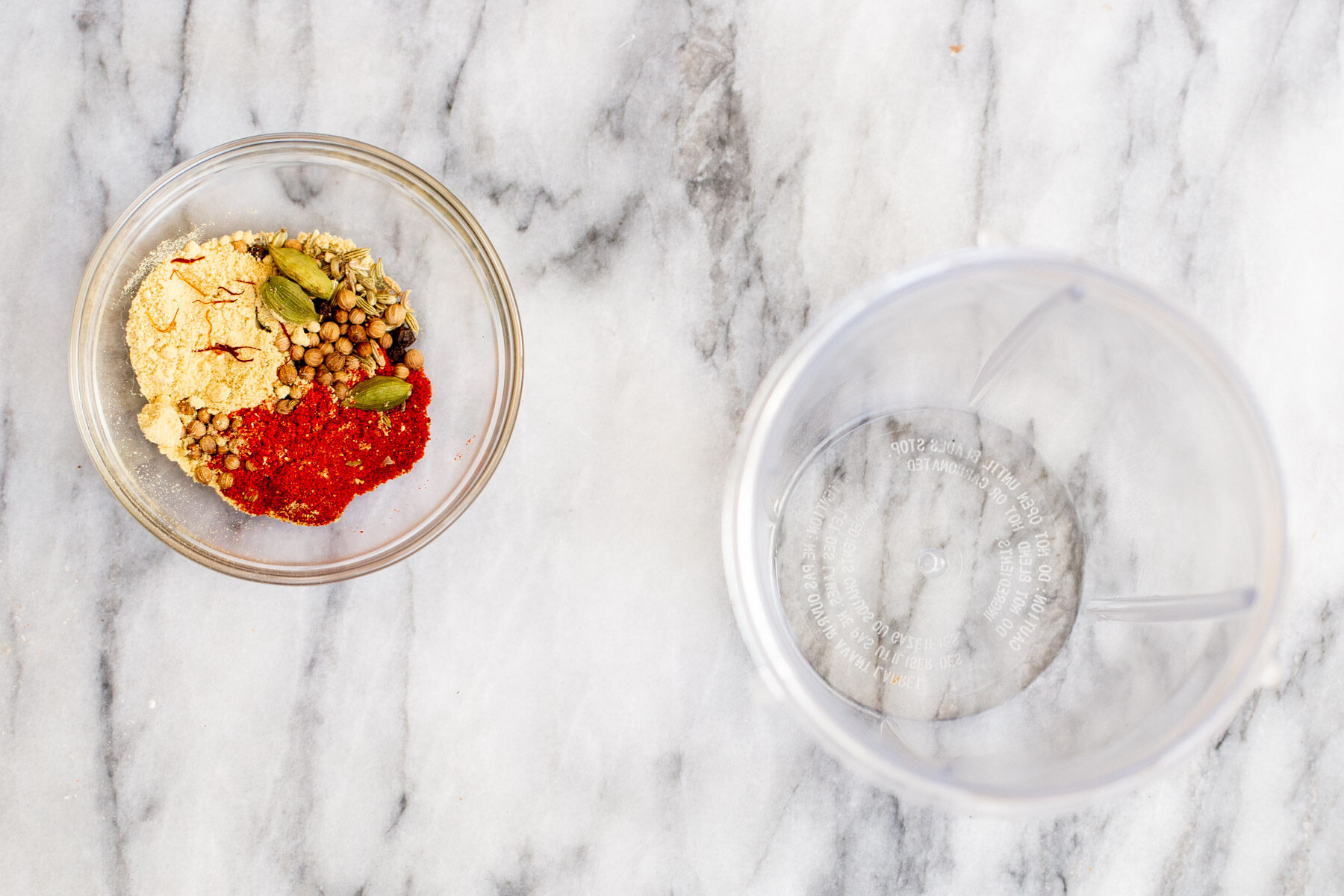 whole Indian spices in a small glass dish on a marble countertop 