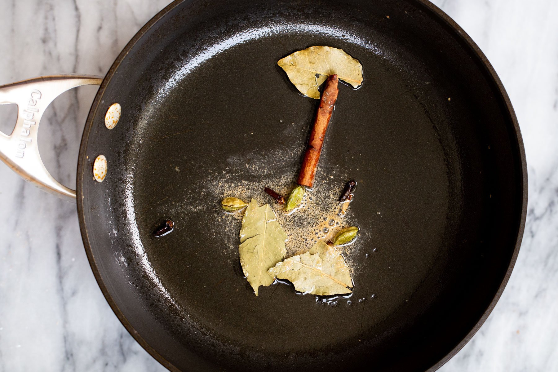 whole Indian spices frying in oil to make tempering 