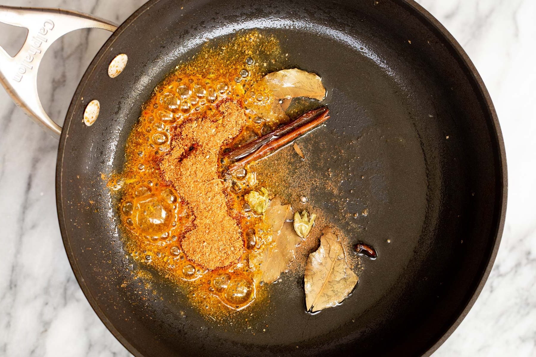 whole spices and ground spices frying in oil 