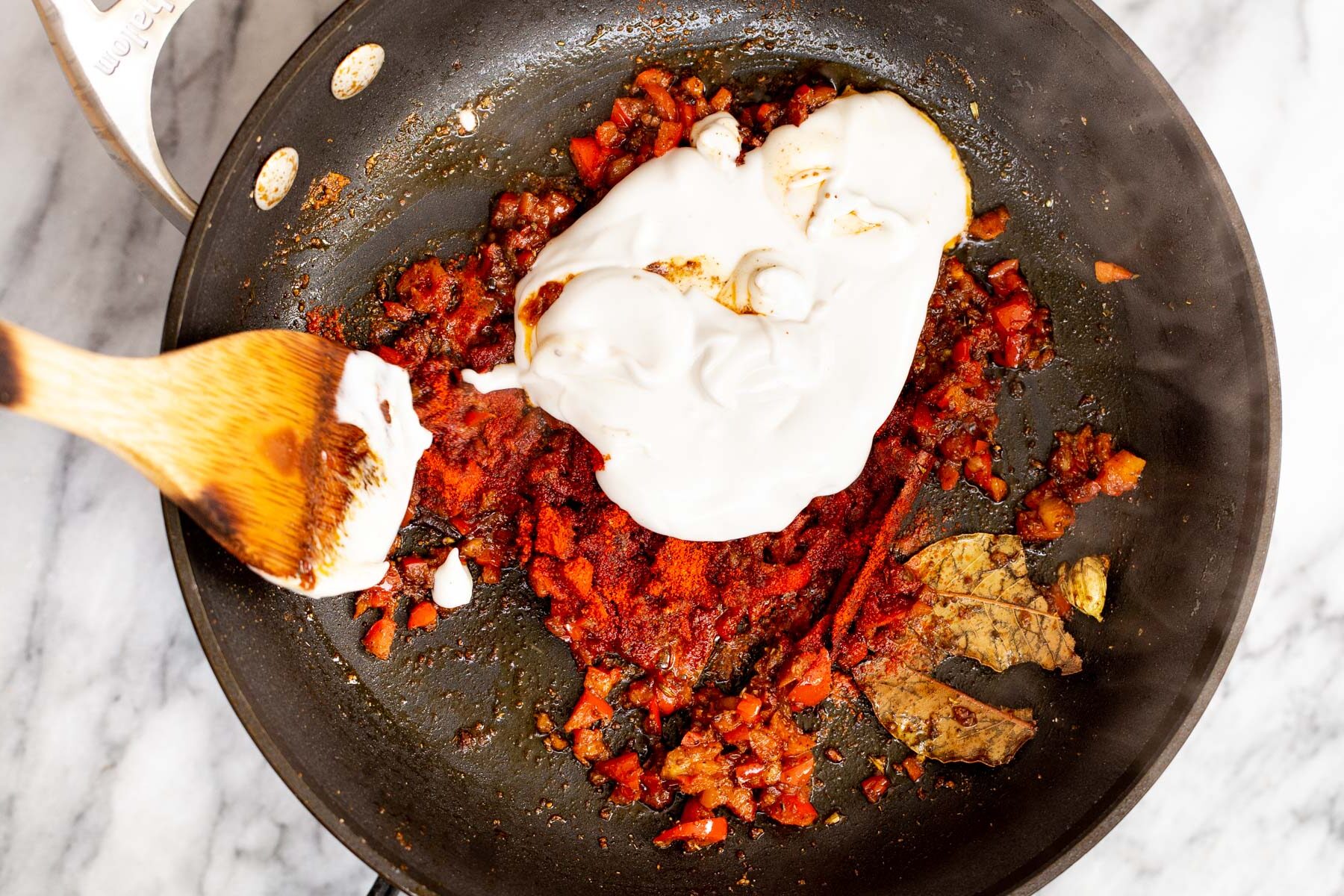 coconut yogurt being added to a sauteeing pan 