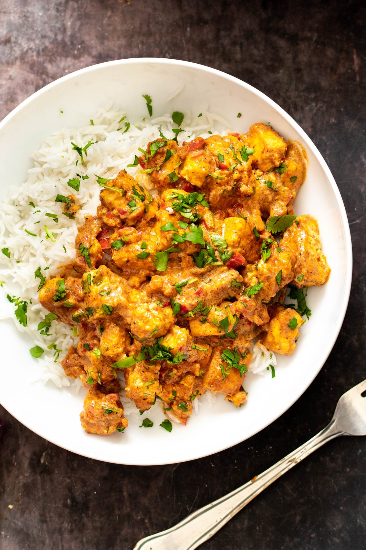 a plate of vegan rogan josh served with a side of rice