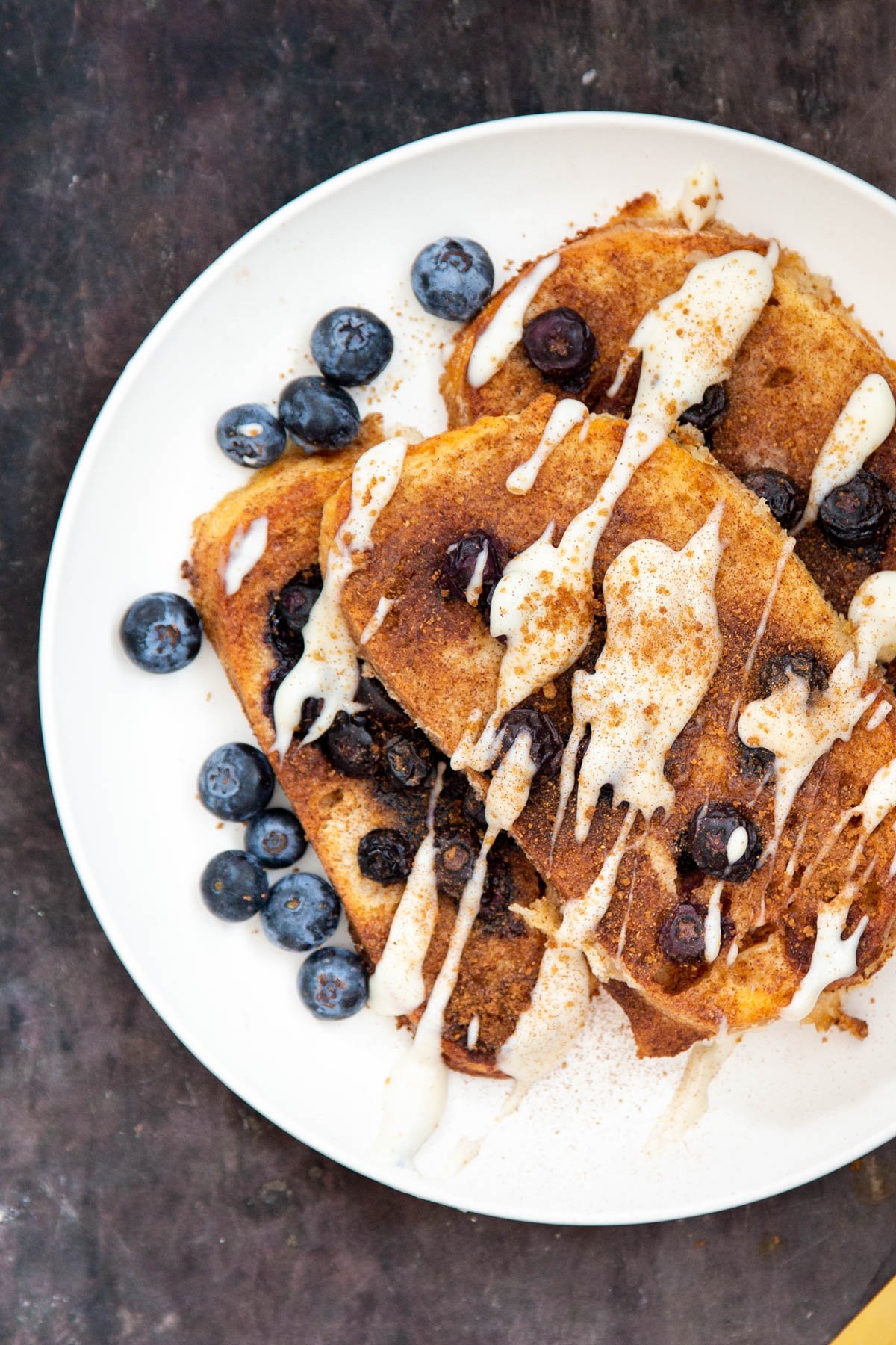 a plate with vegan baked French Toast drizzled with custard and sprinkled with blueberries