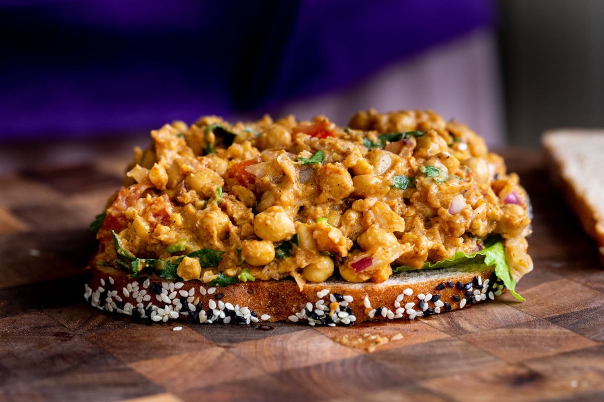 curried chickpeas salad being spread on a slice of bread