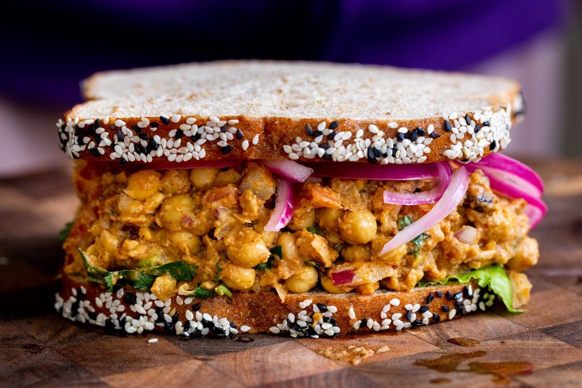 a side view of a vegan curried egg salad sandwich on a chopping board