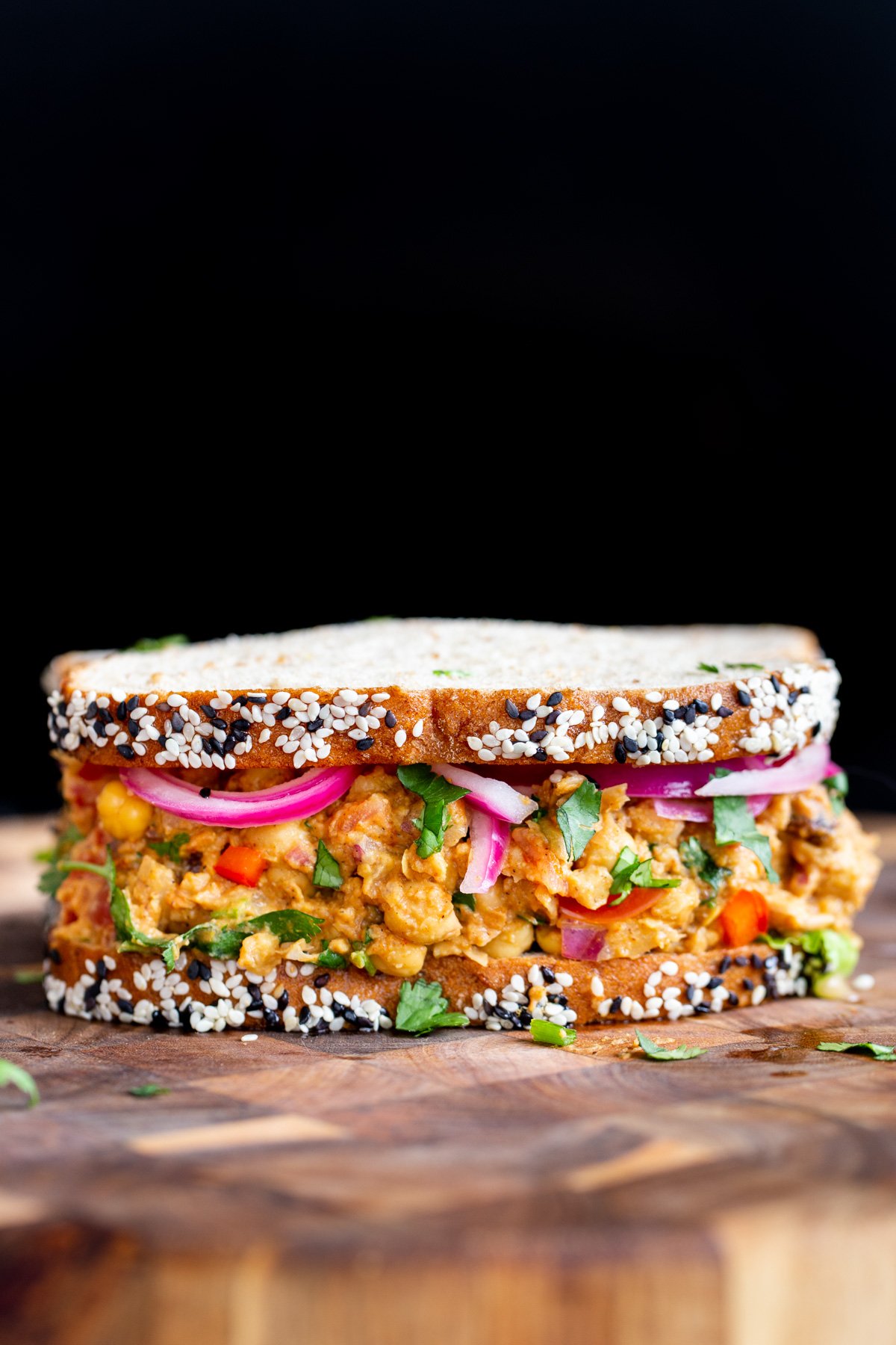 a vegan egg salad sandwich on a wooden chopping board