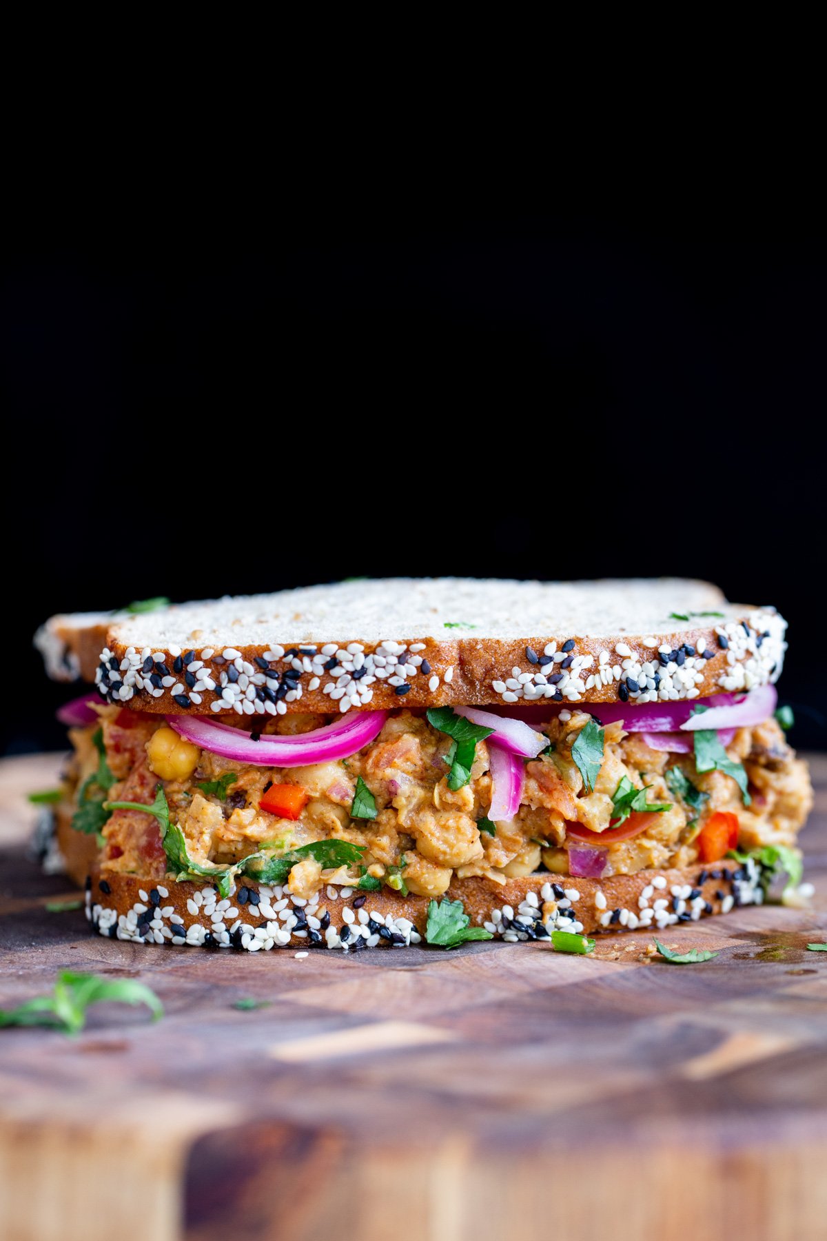 side view of a vegan curried chickpea salad sandwich on a chopping board