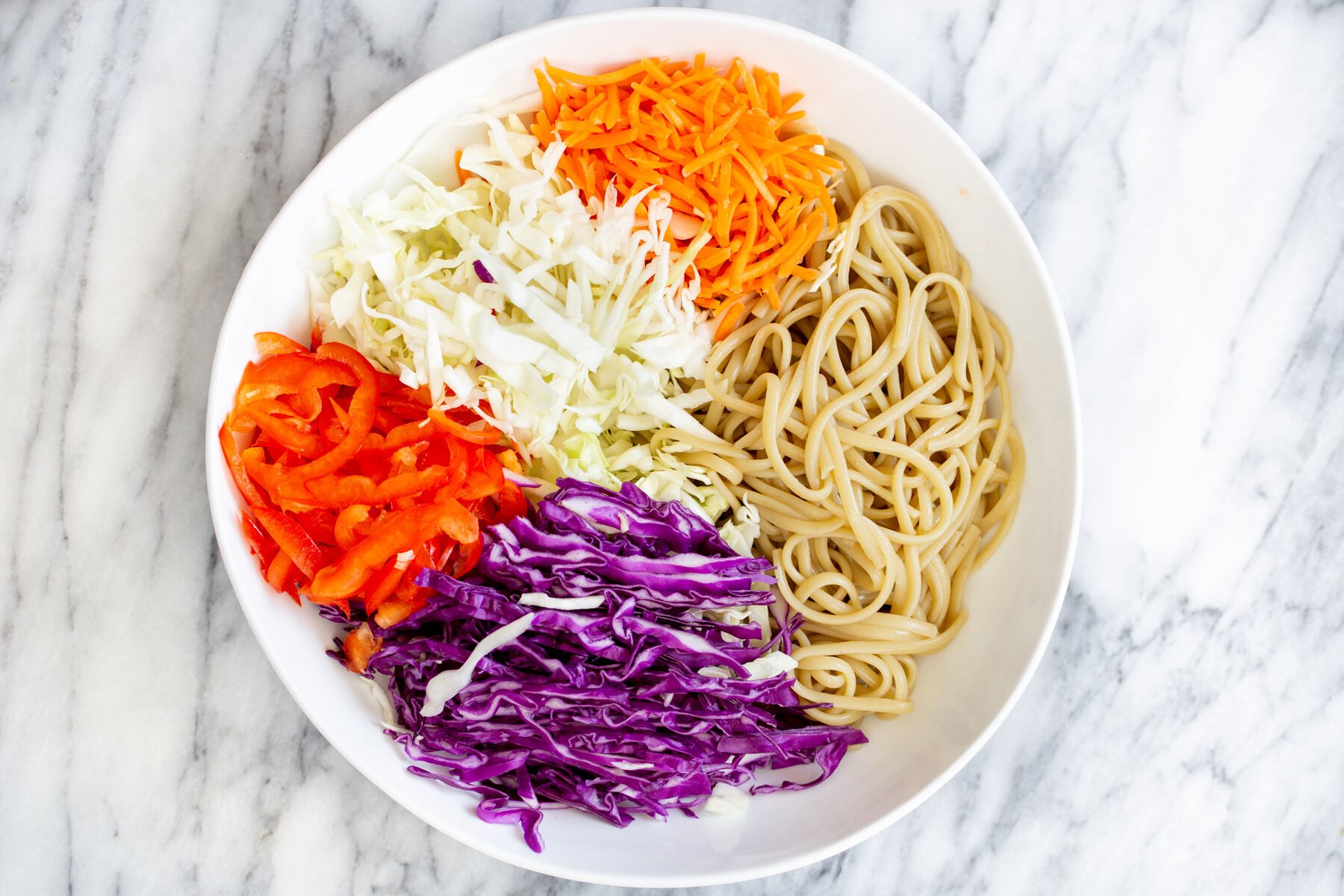 peanut sesame noodle salad ingredients in a white bowl