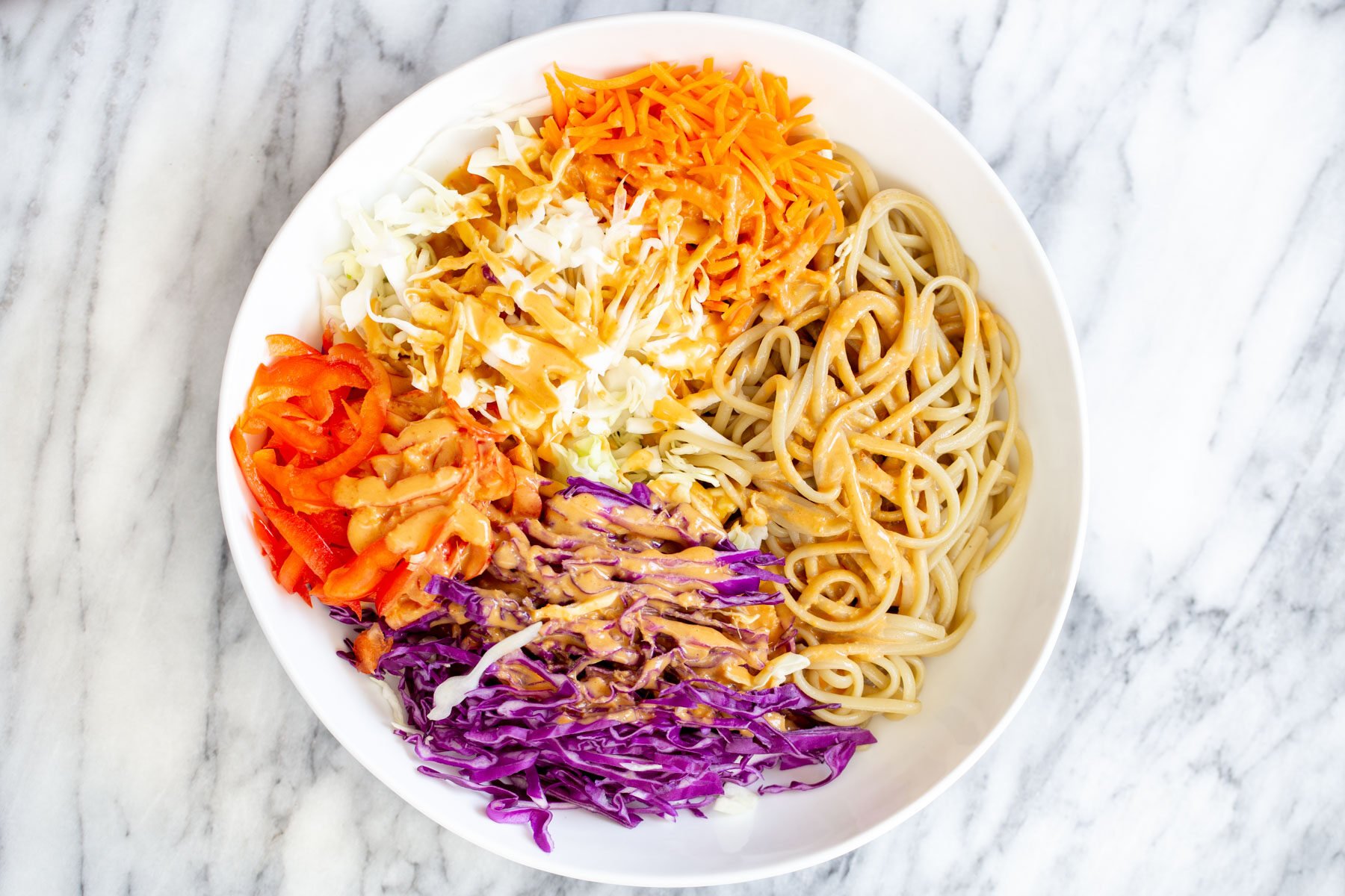 peanut sesame noodle salad with chopped veggies drizzled with peanut butter dressing