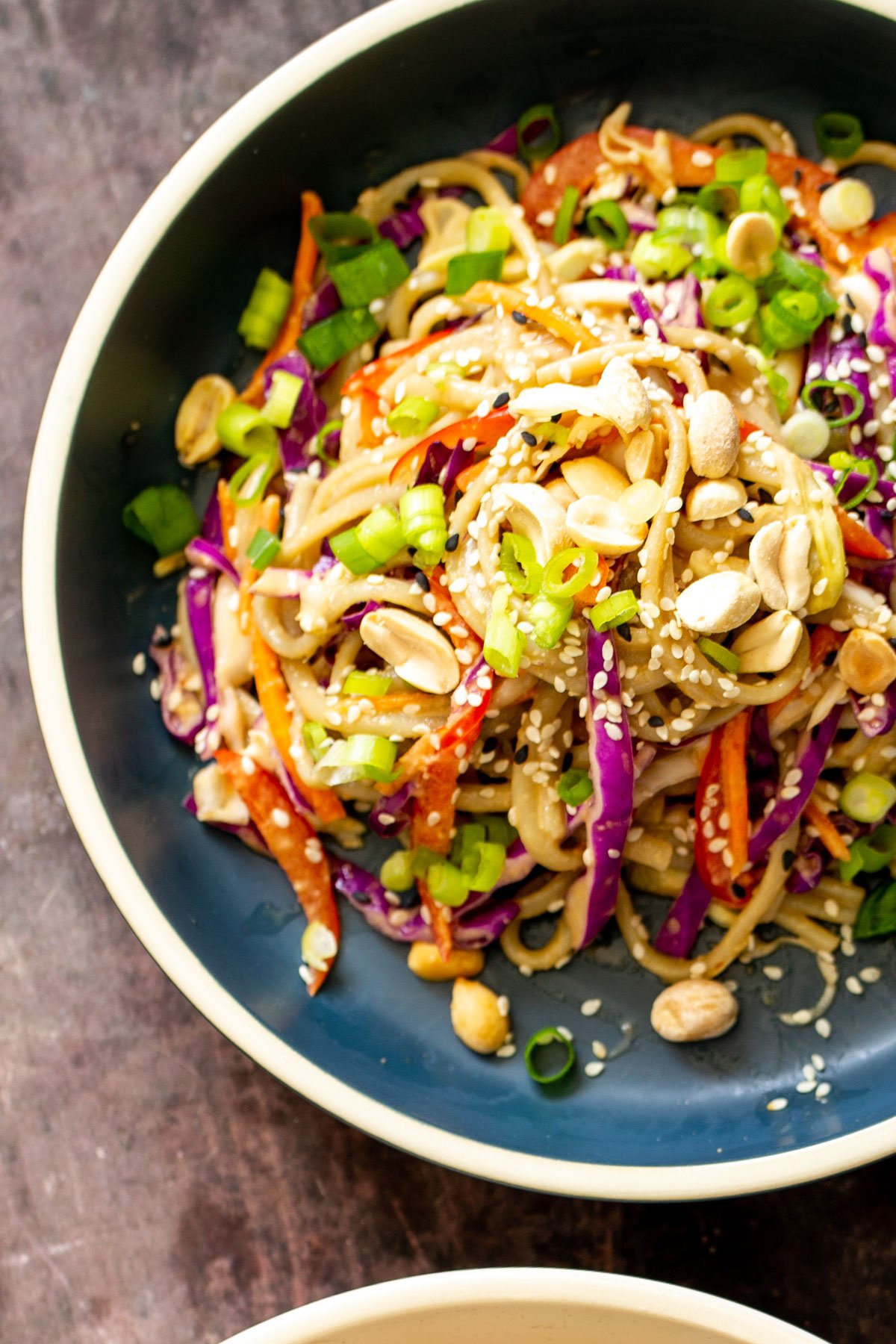 peanut sesame noodle salad with vegetables sprinkled with sesame seeds and peanuts