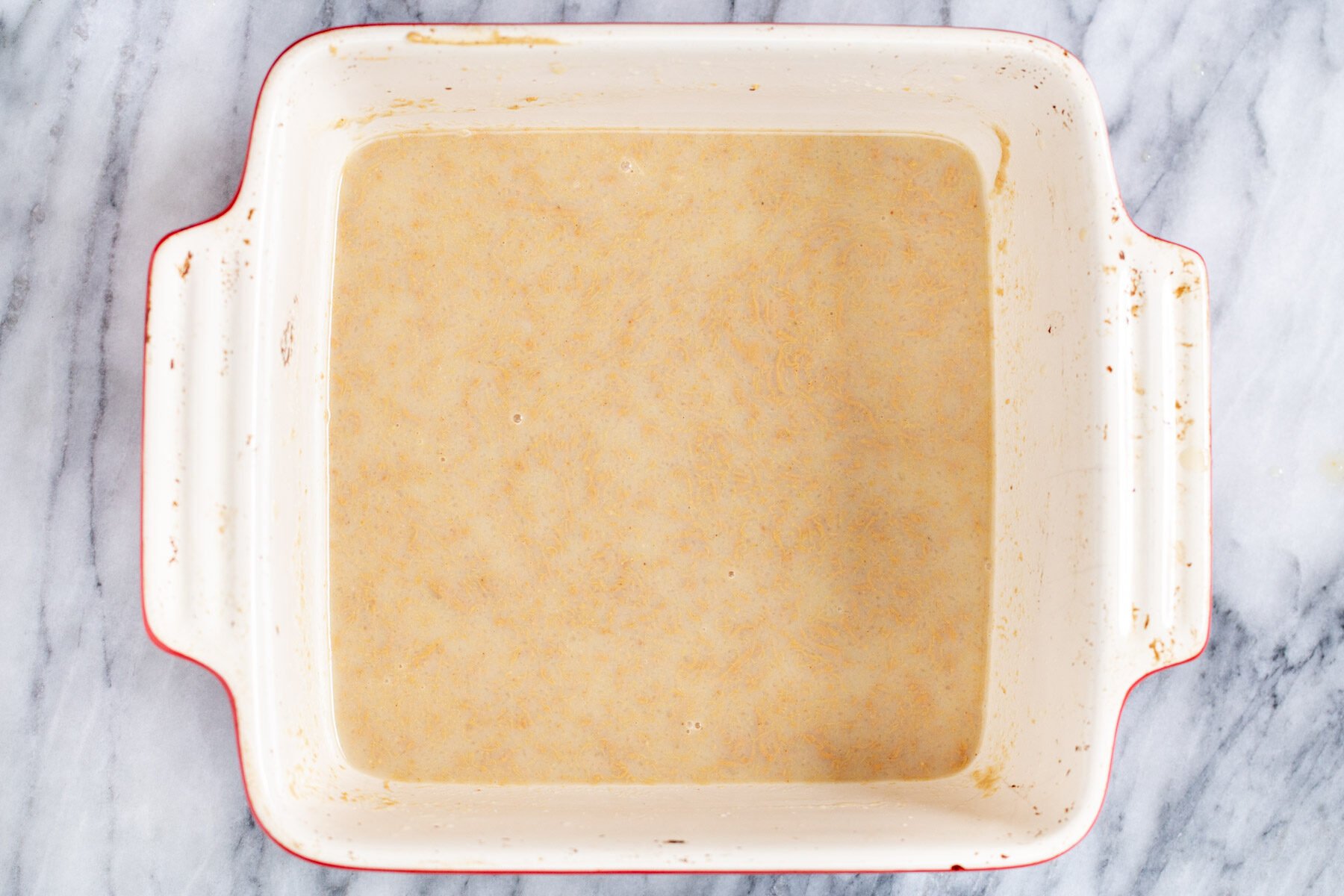 peanut butter being dissolved in hot milk in a casserole dish