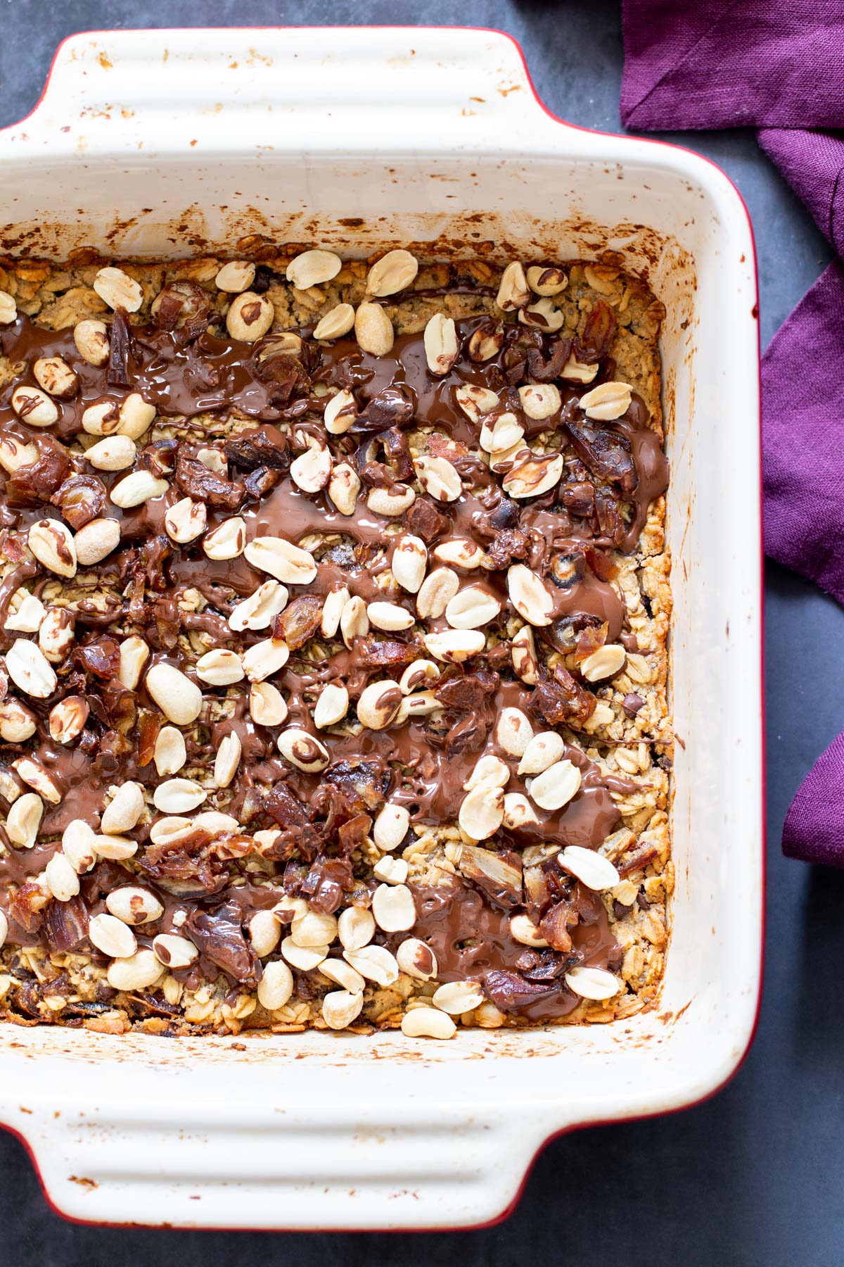 snickers baked oatmeal  snickers baked oatmeal topped with peanuts and chocolate in a casserole dish