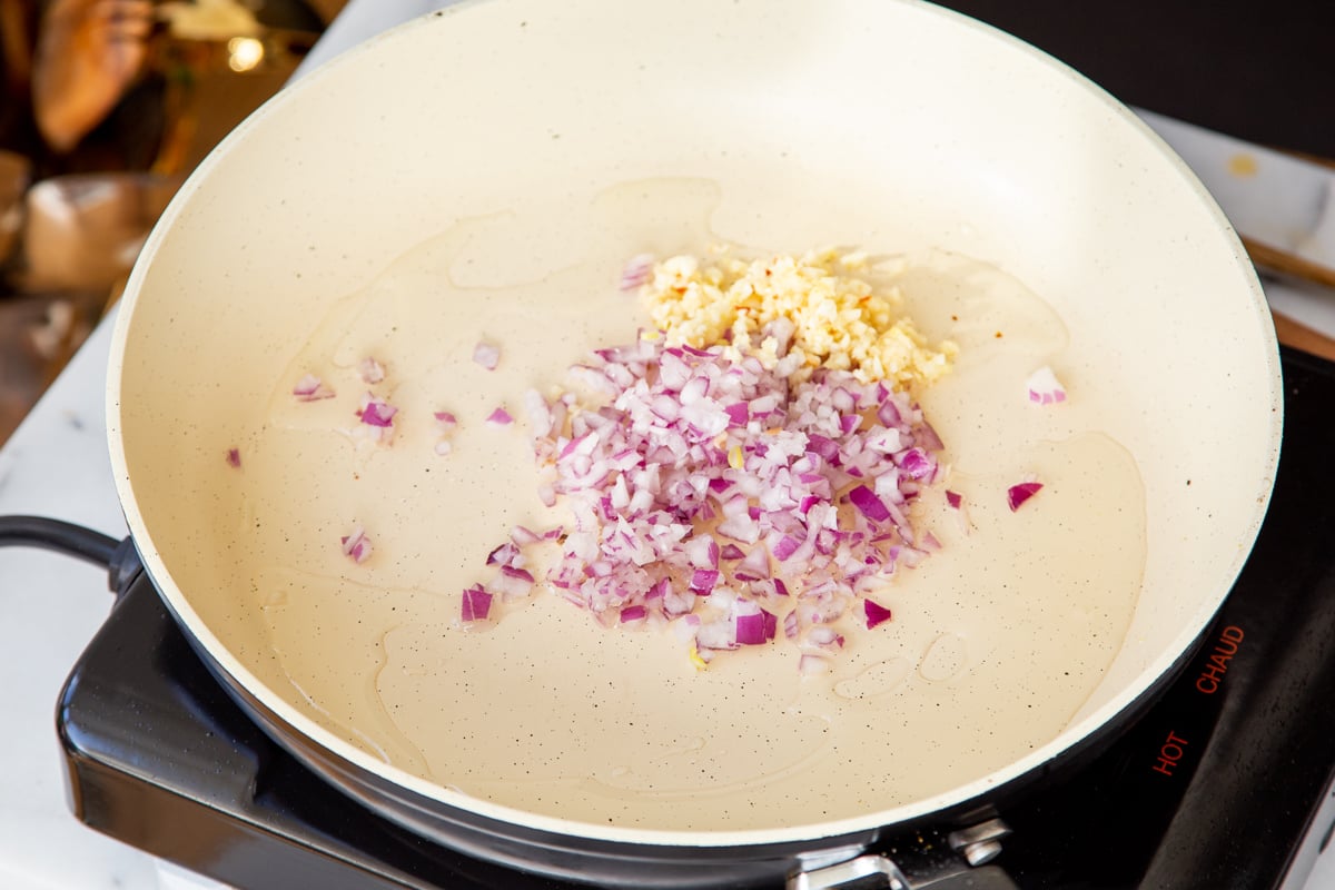 chopped onions and garlic being sauteed in a pan