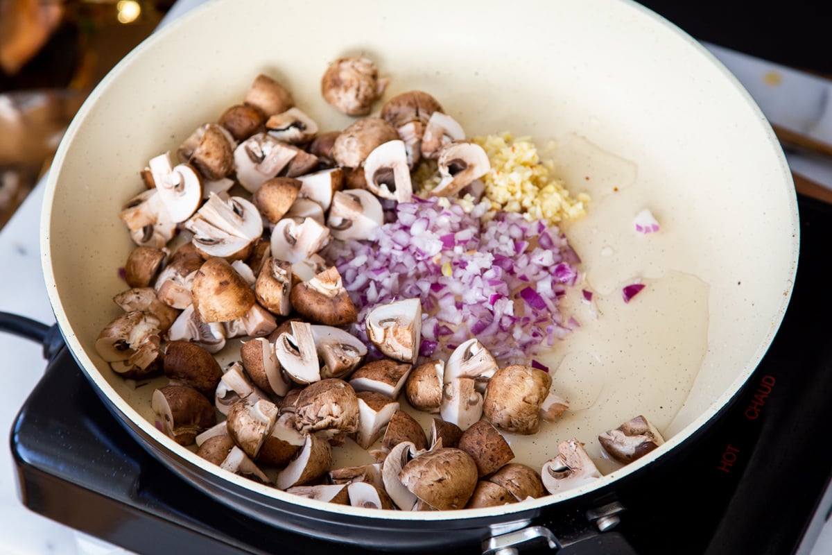 garlic, onion and mushrooms being sauteed in a pan