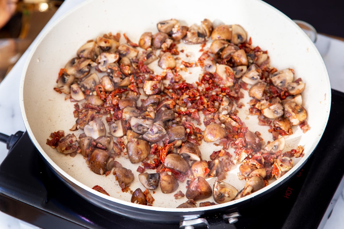 sauteed mushrooms and sundried tomatoes in a frying pan