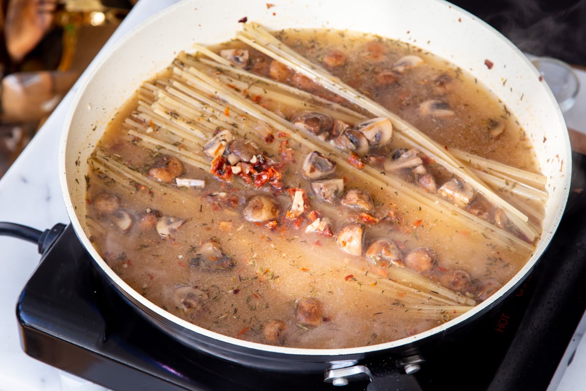 fettuccine being cooked in mushroom sundried tomato sauce