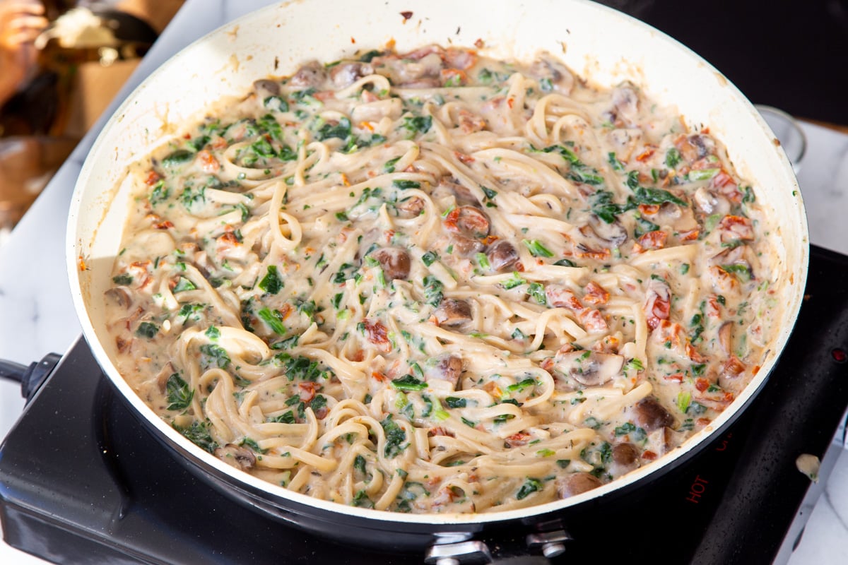 creamy spinach mushroom and sundried tomato pasta in a saucepan