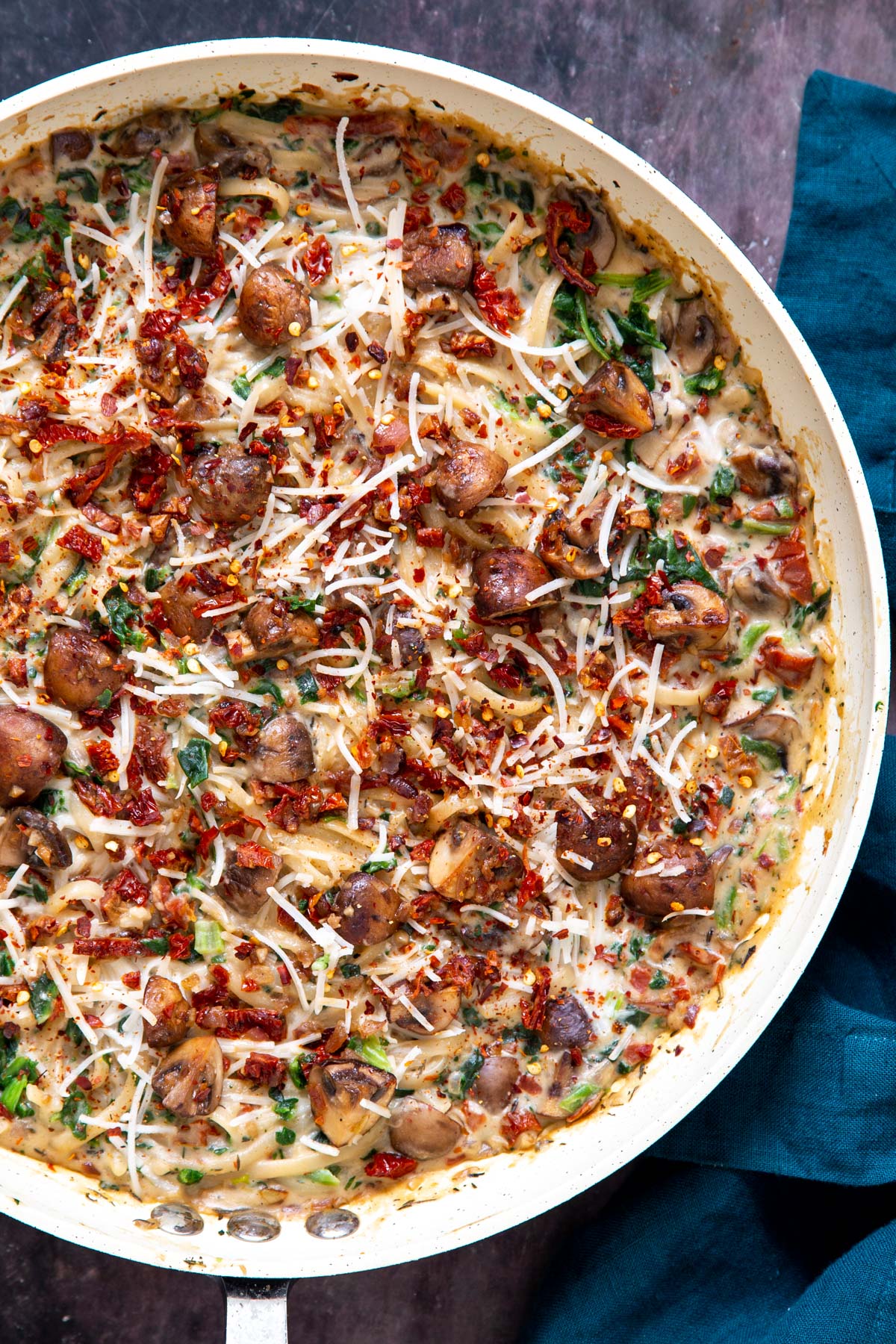 overhead shot of a saucepan with creamy vegan mushroom pasta with sundried tomatoes and spinach
