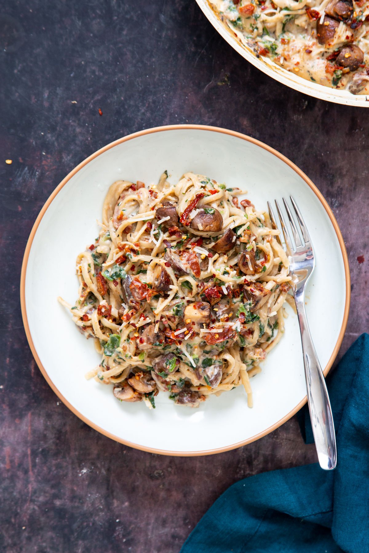 a plate of creamy vegan mushroom pasta topped with sundried tomatoes and sauteed mushrooms