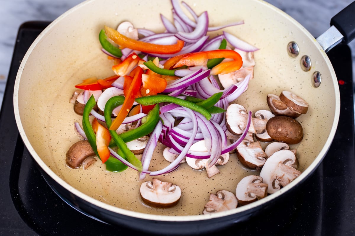 sliced veggies being added to a sauteeing pan