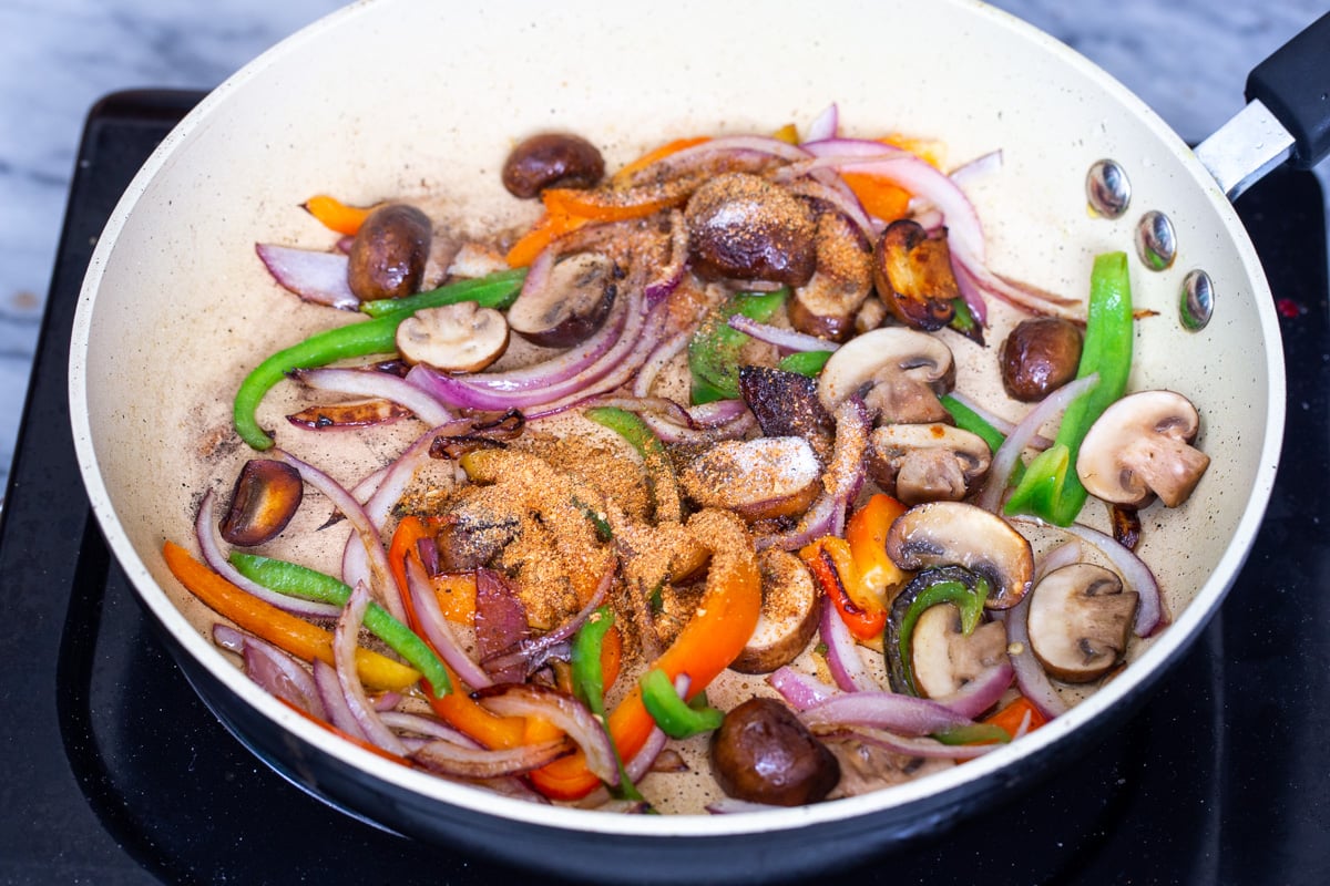 sliced veggies in a sauteeing pan sprinkled with spices