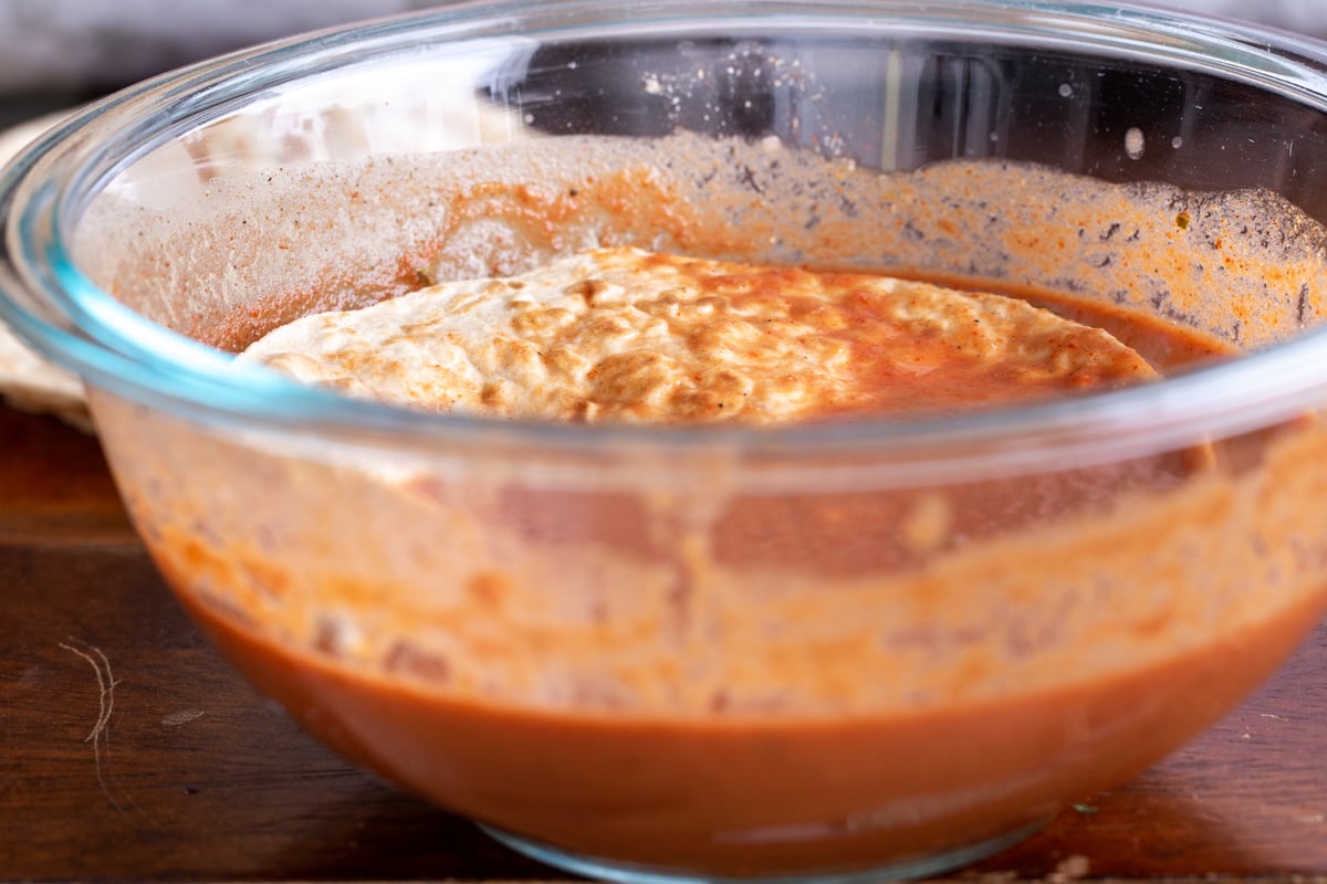 tortilla being dipped into a small glass dish with masala gravy