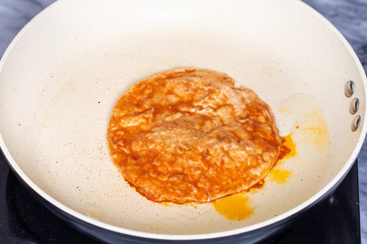 tortilla in a sauteeing pan dipped into gravy