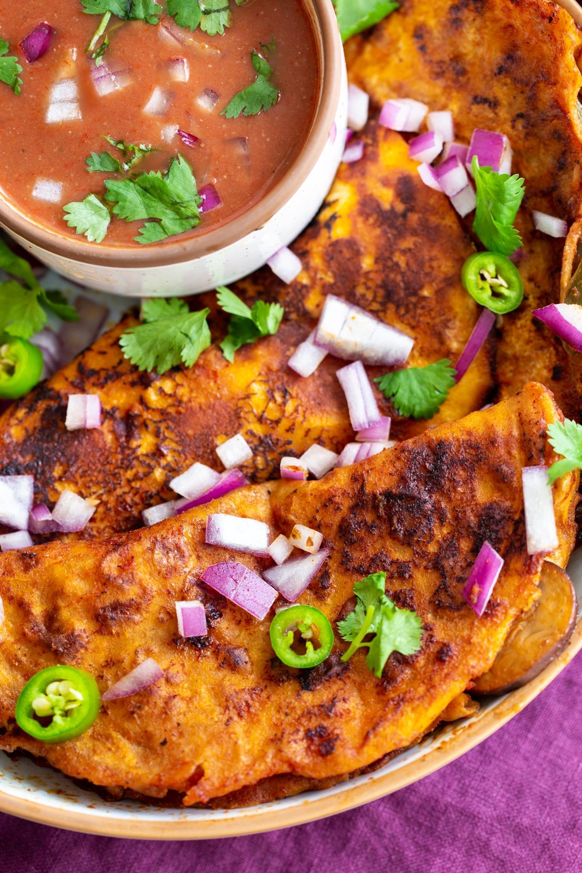 vegan birria tacos served with a small dish of vegan masala gravy