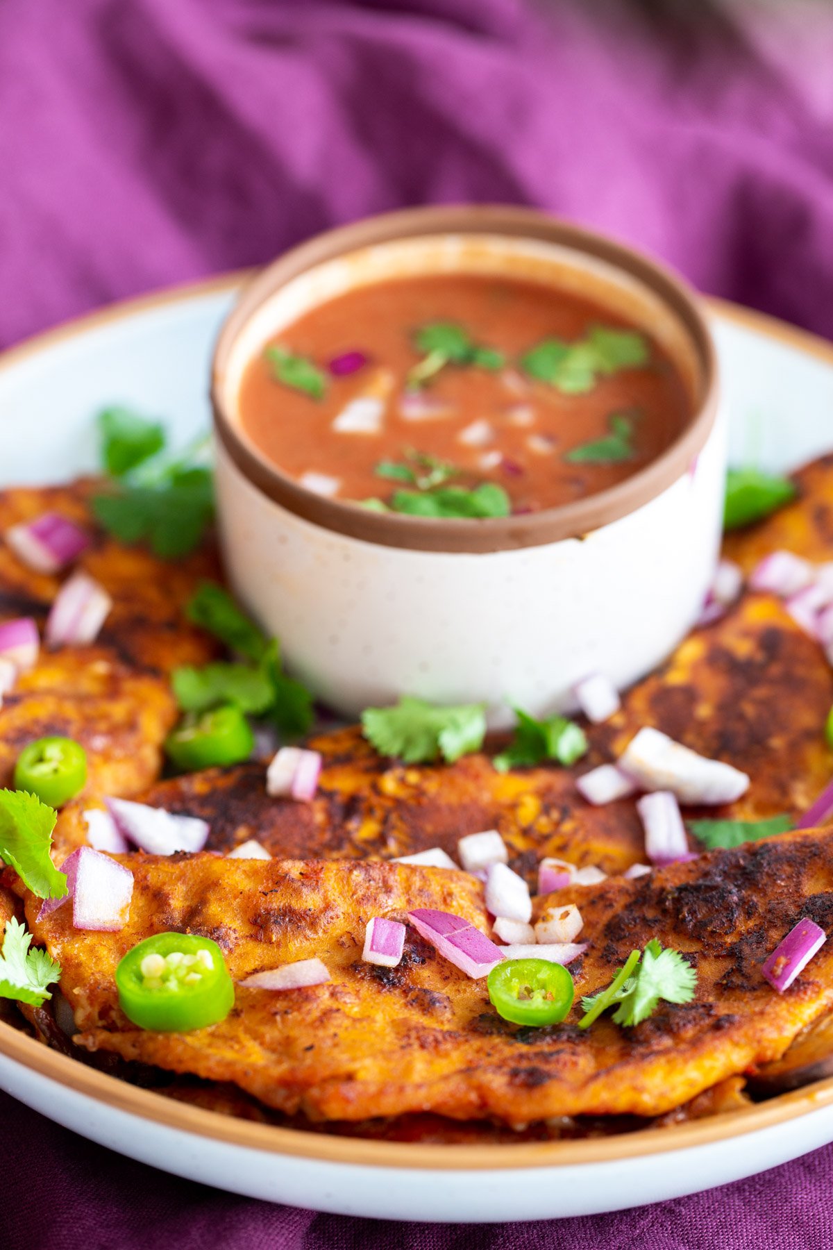 a plate of vegan birria tacos with a small side dish of masala gravy