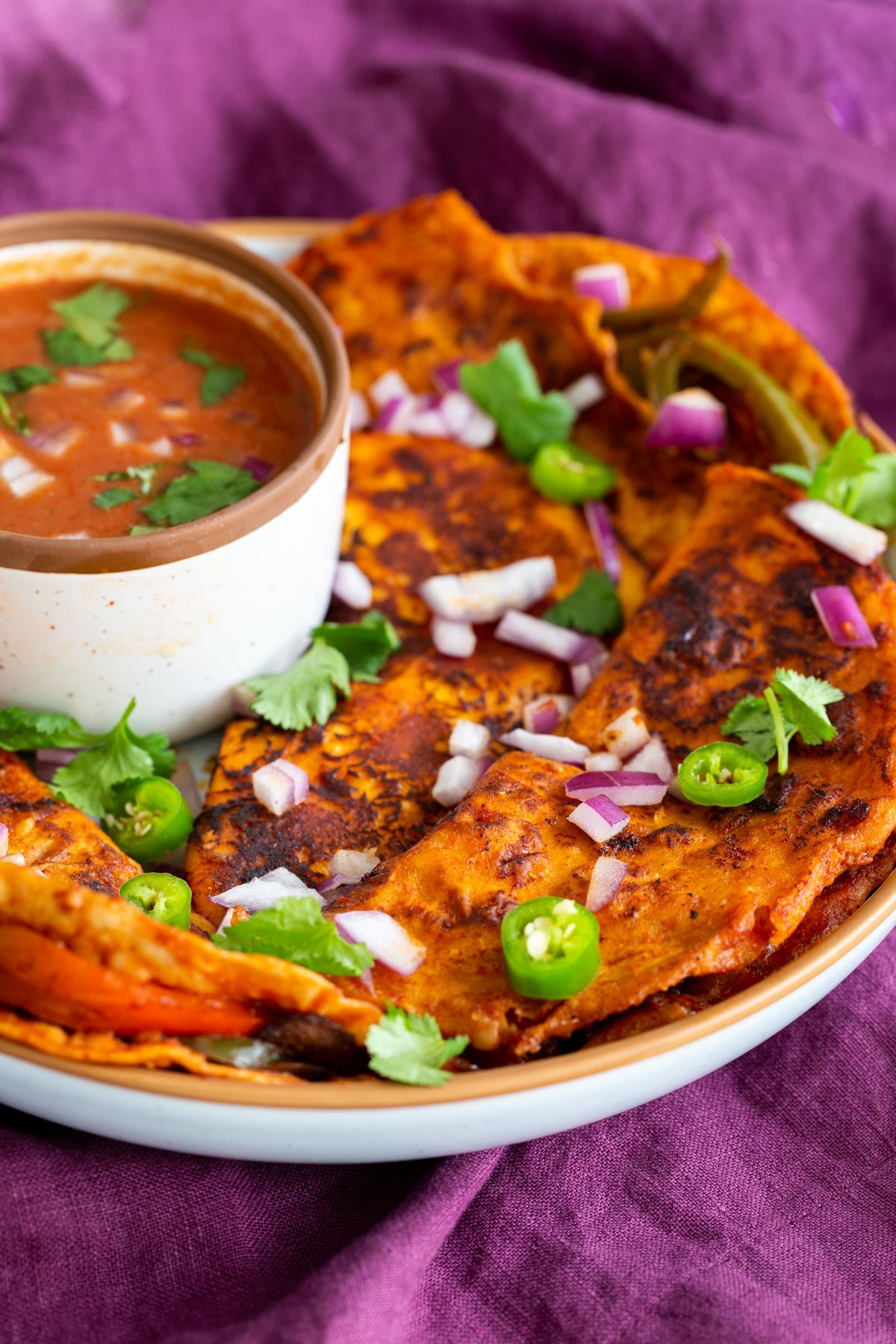 a plate of vegan birria tacos with a side dish of masala sauce