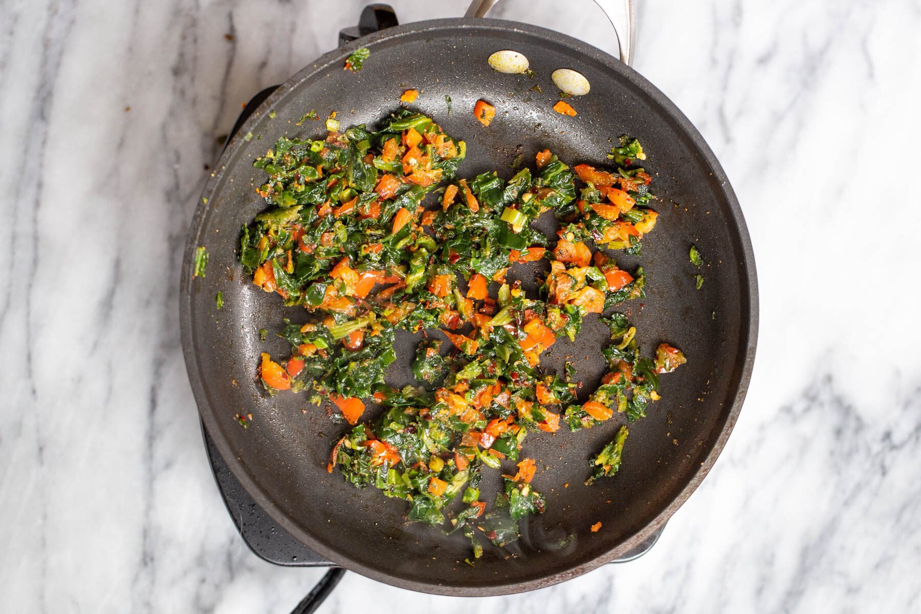 spinach and tomatoes in a black sauteeing pan