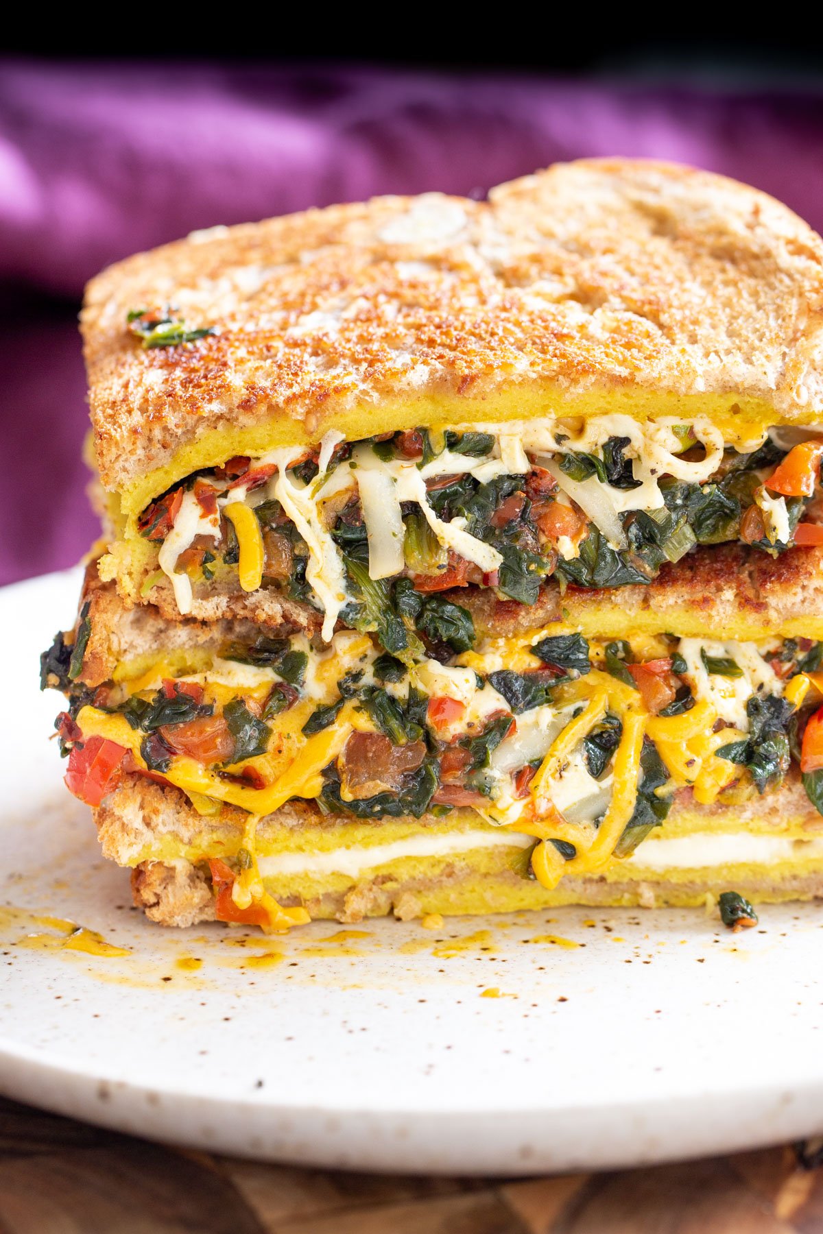 slacked spinach and cheese vegan egg sandwich on a white plate