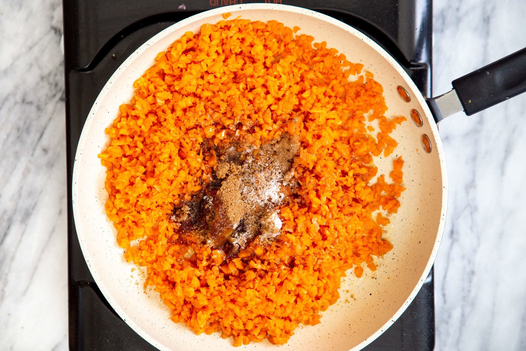 shredded carrots, sugar and maple syrup in a sauteeing pan