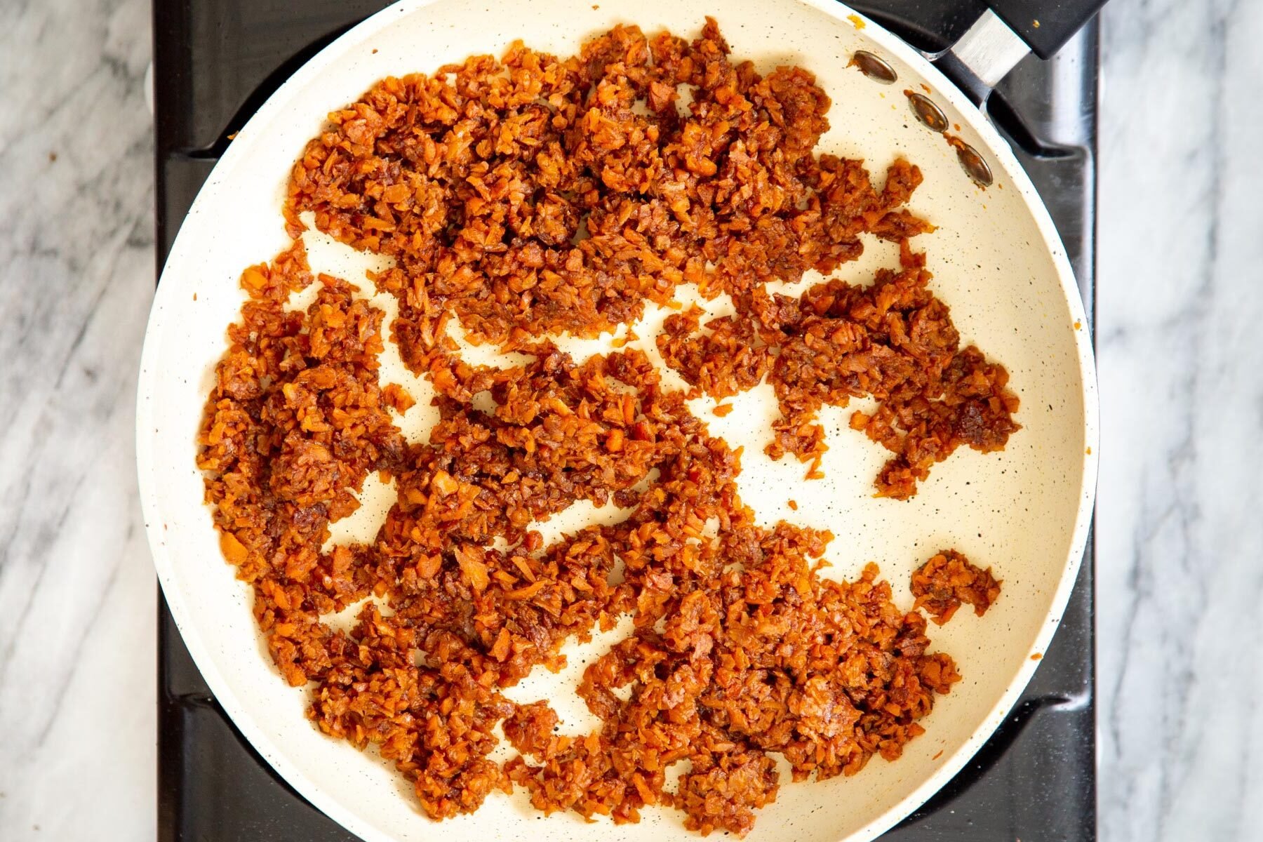 caramelized shredded carrots in a white frying pan