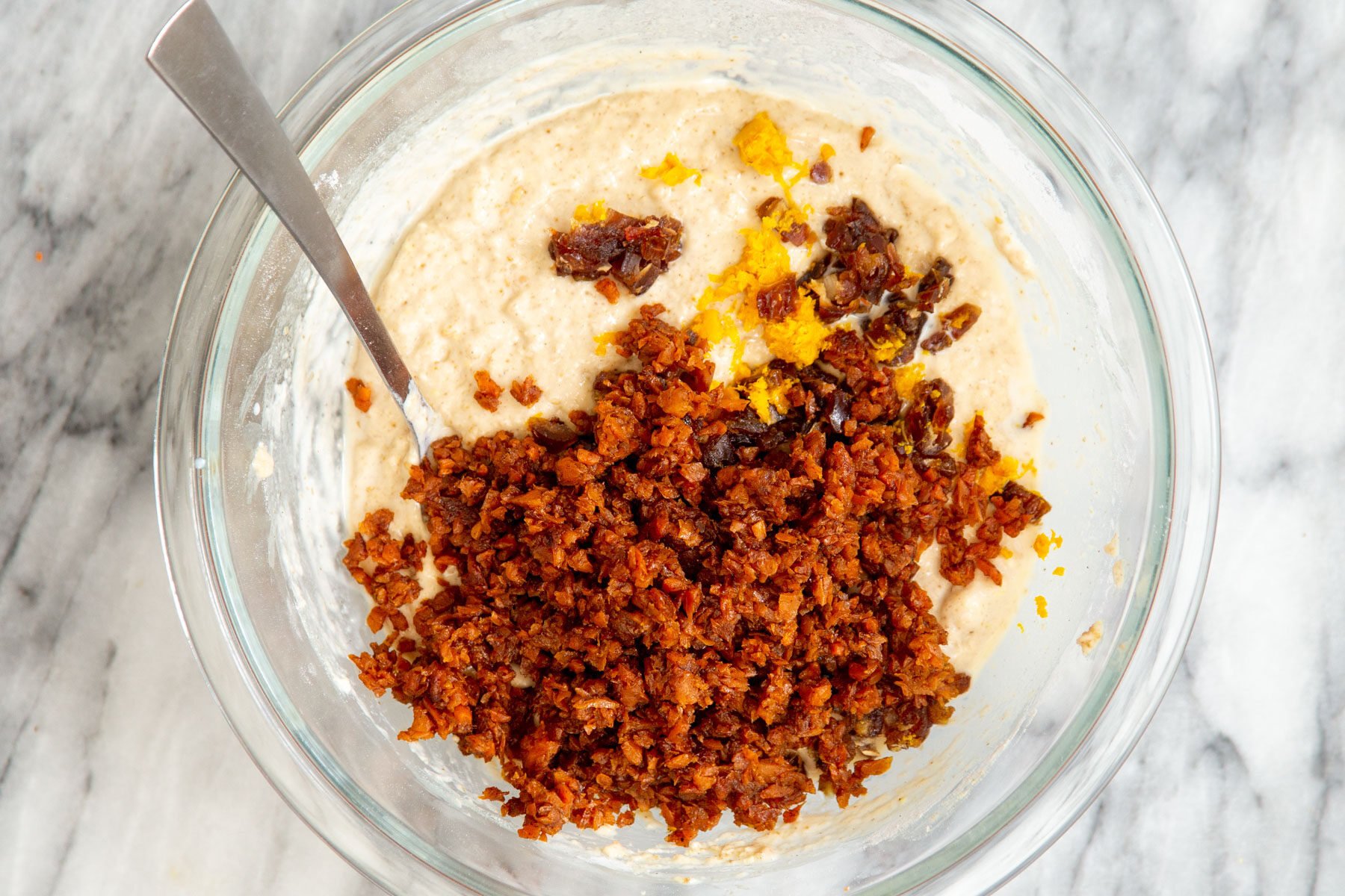 carrots and orange zest being added to carrot cake batter