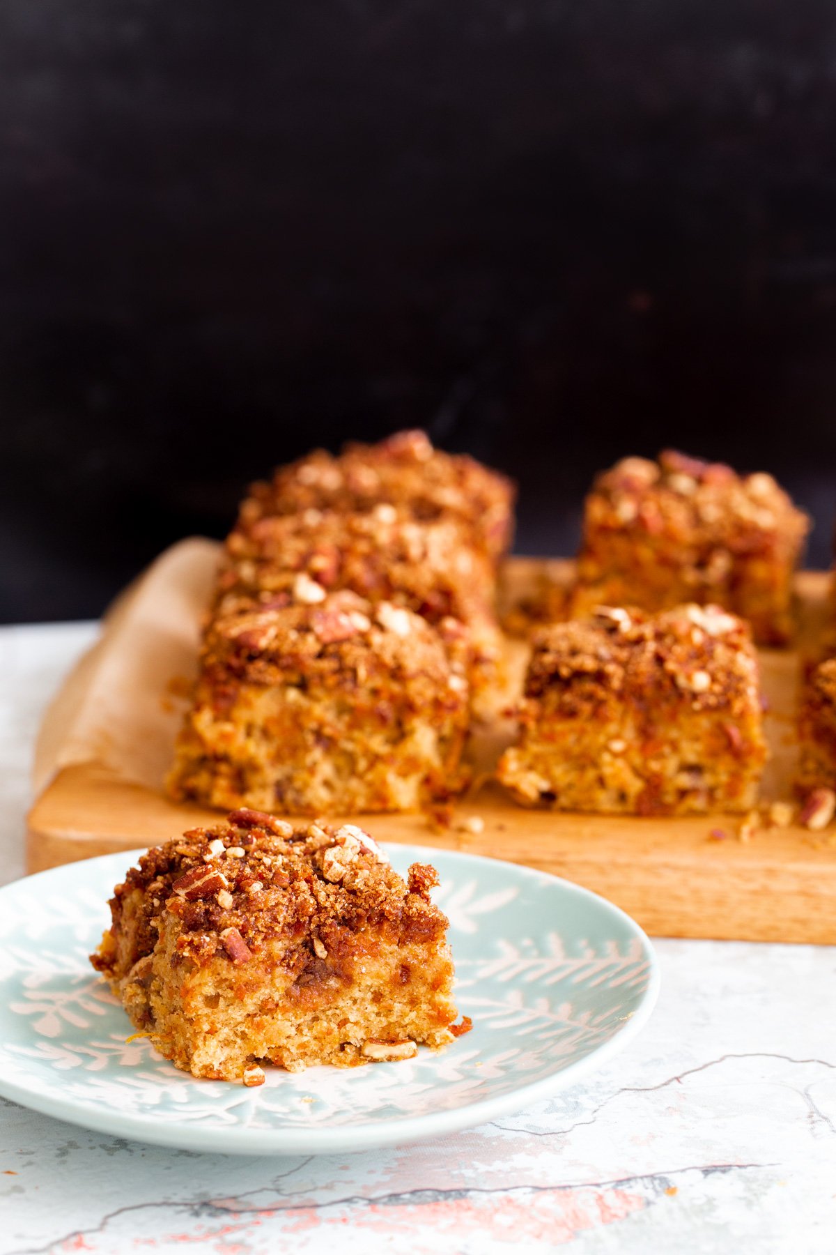 a square slice of vegan carrot cake bar on a white and blue cake plate
