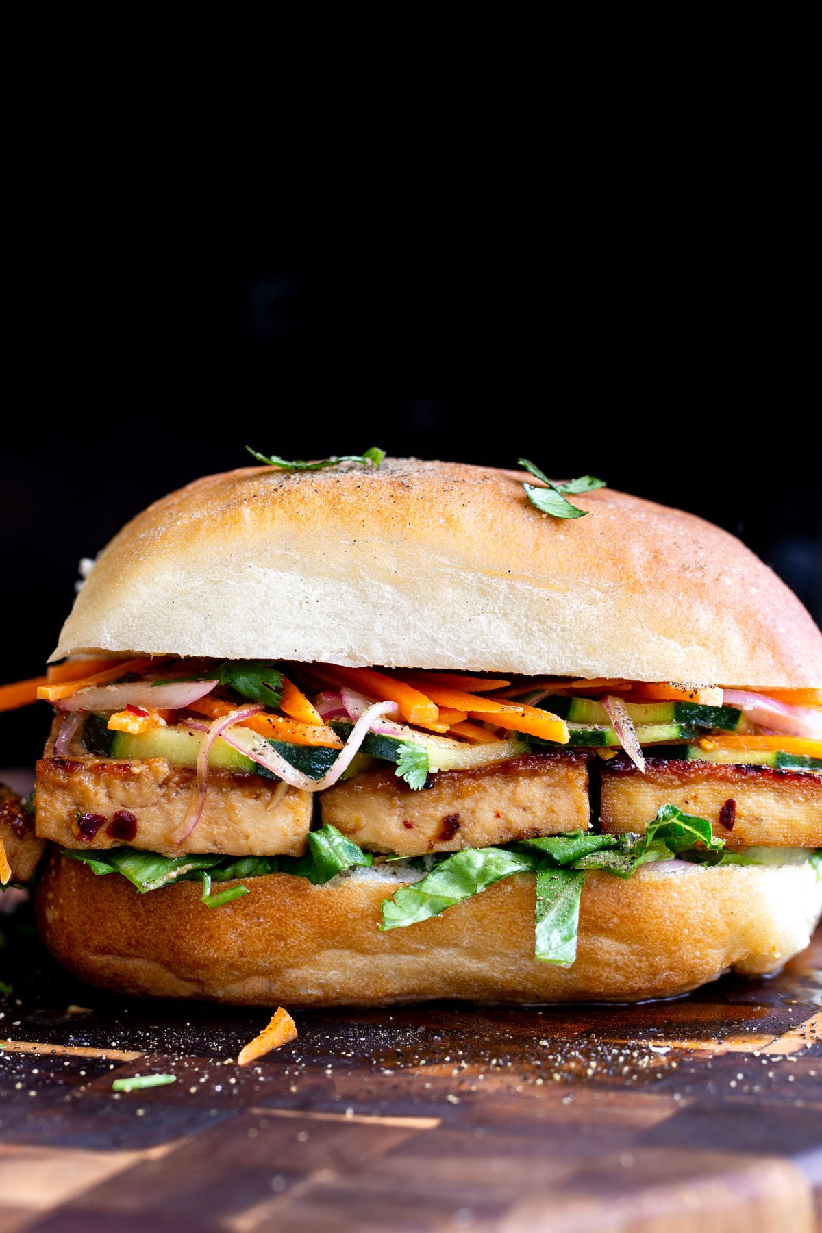 side view of vegan garlic chili tofu sandwich on a chopping board