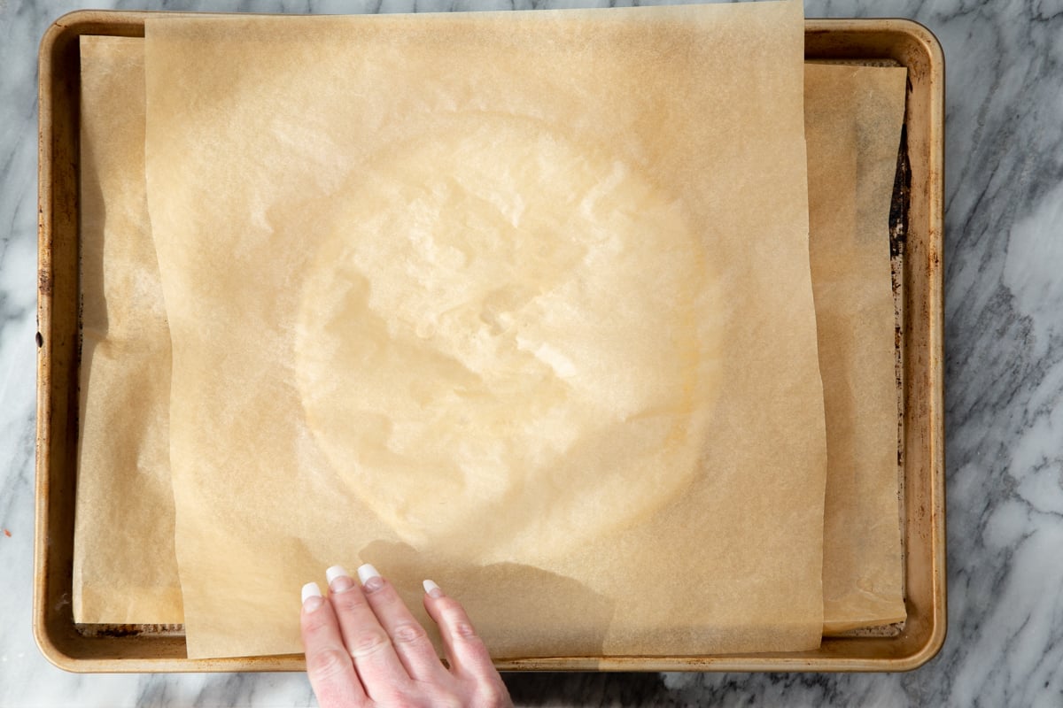parchment paper being placed on an round of almond flour pizza crust
