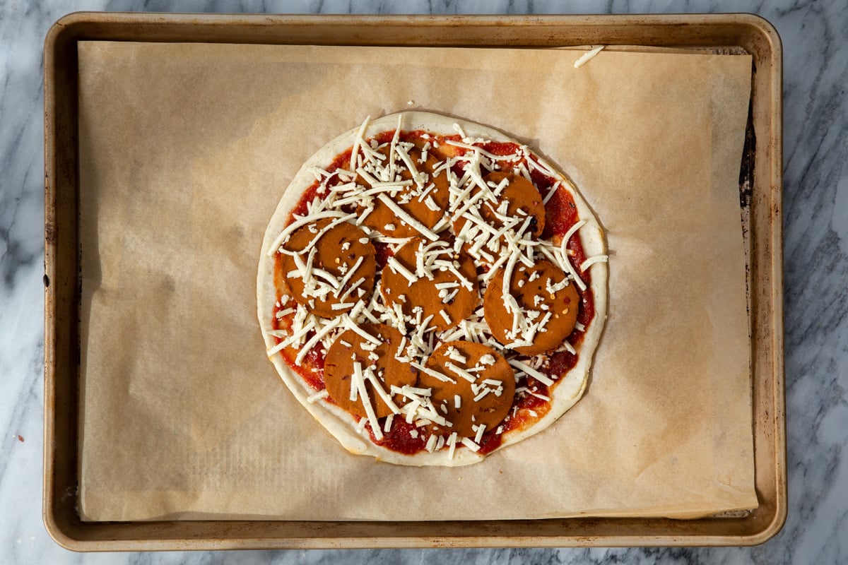 almond flour pizza crust being topped with pepperoni and cheese