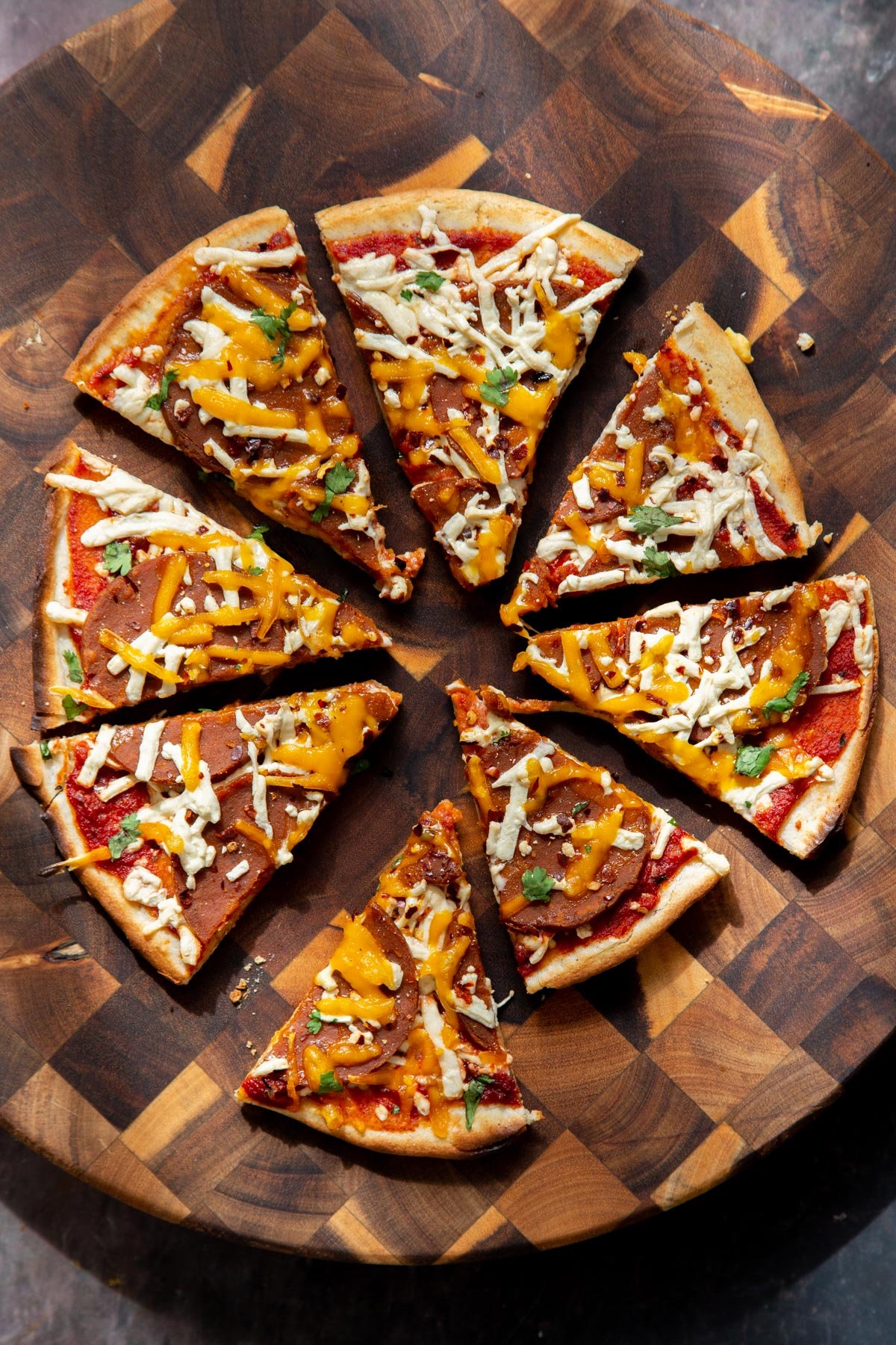 vegan pepperoni pizza on a wooden board, sliced.