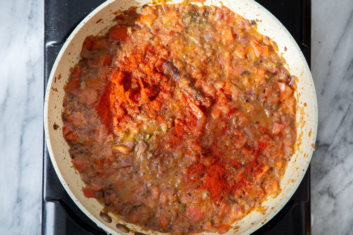 chili powder and paprika being added to frying pan